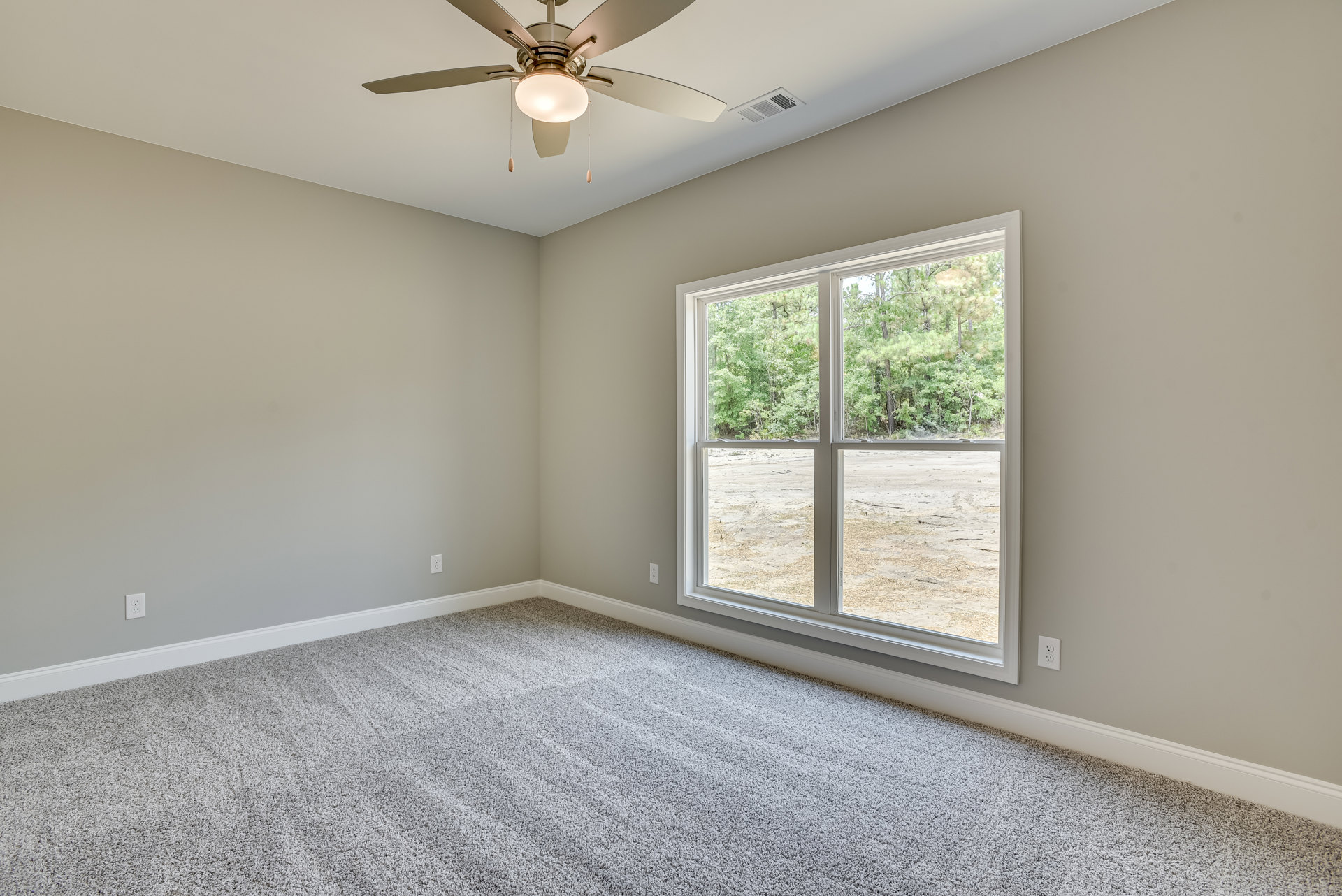 Carpeted room with white walls, ceiling fan with light fixture, large window overlooking green trees, crown molding along ceiling edges