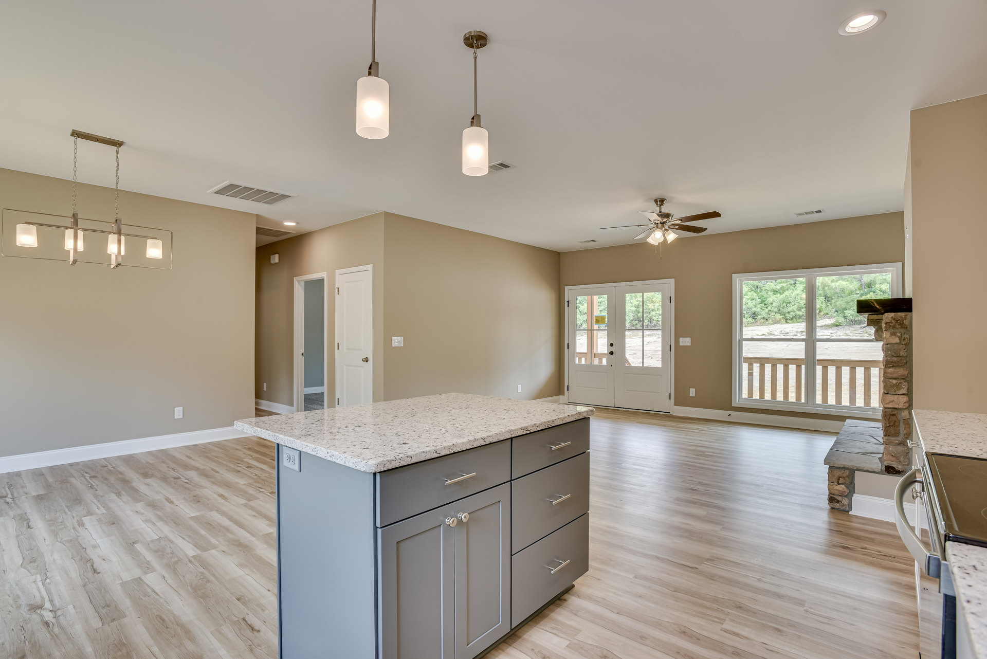 Marble kitchen island with built-in sink, white cabinetry, tile flooring, glass-paneled double doors, and ceiling light fixture.
