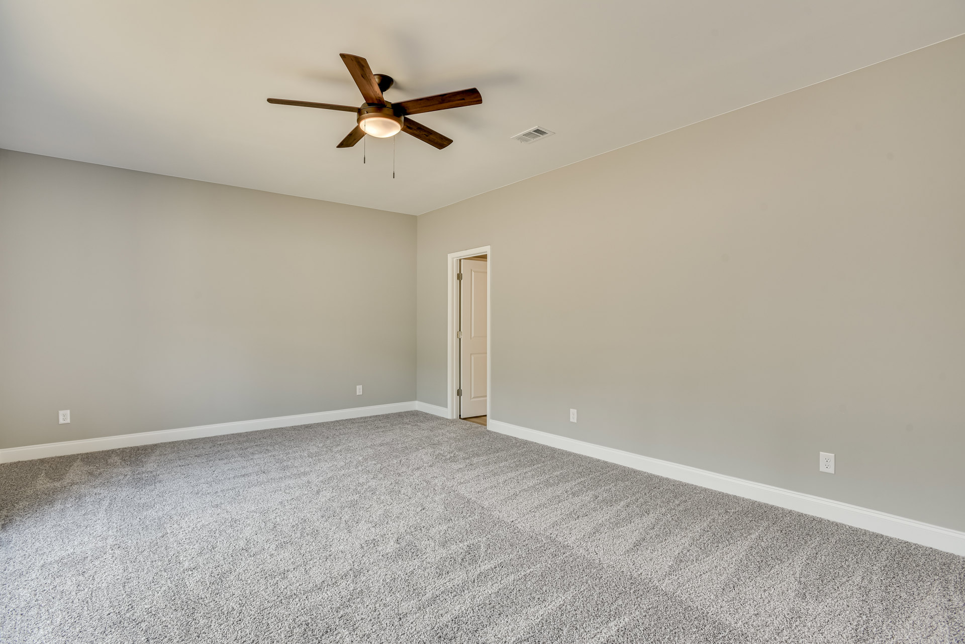 Carpeted room with white walls, ceiling fan with light fixture, wood beam detail, and paneled door