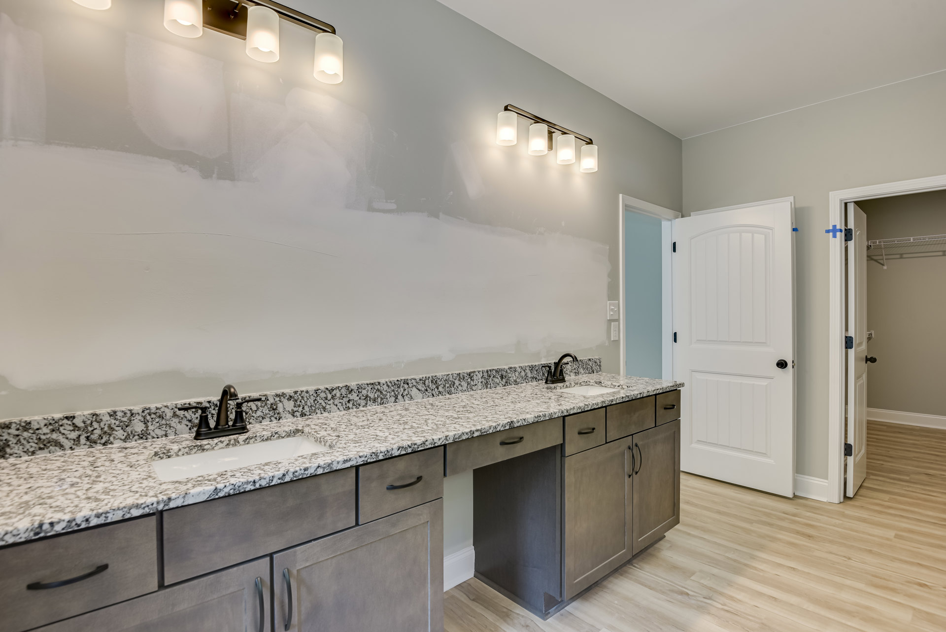 Bathroom featuring marble countertop with undermount sink, chrome faucet, white cabinetry, black hardware, white door, and tile flooring
