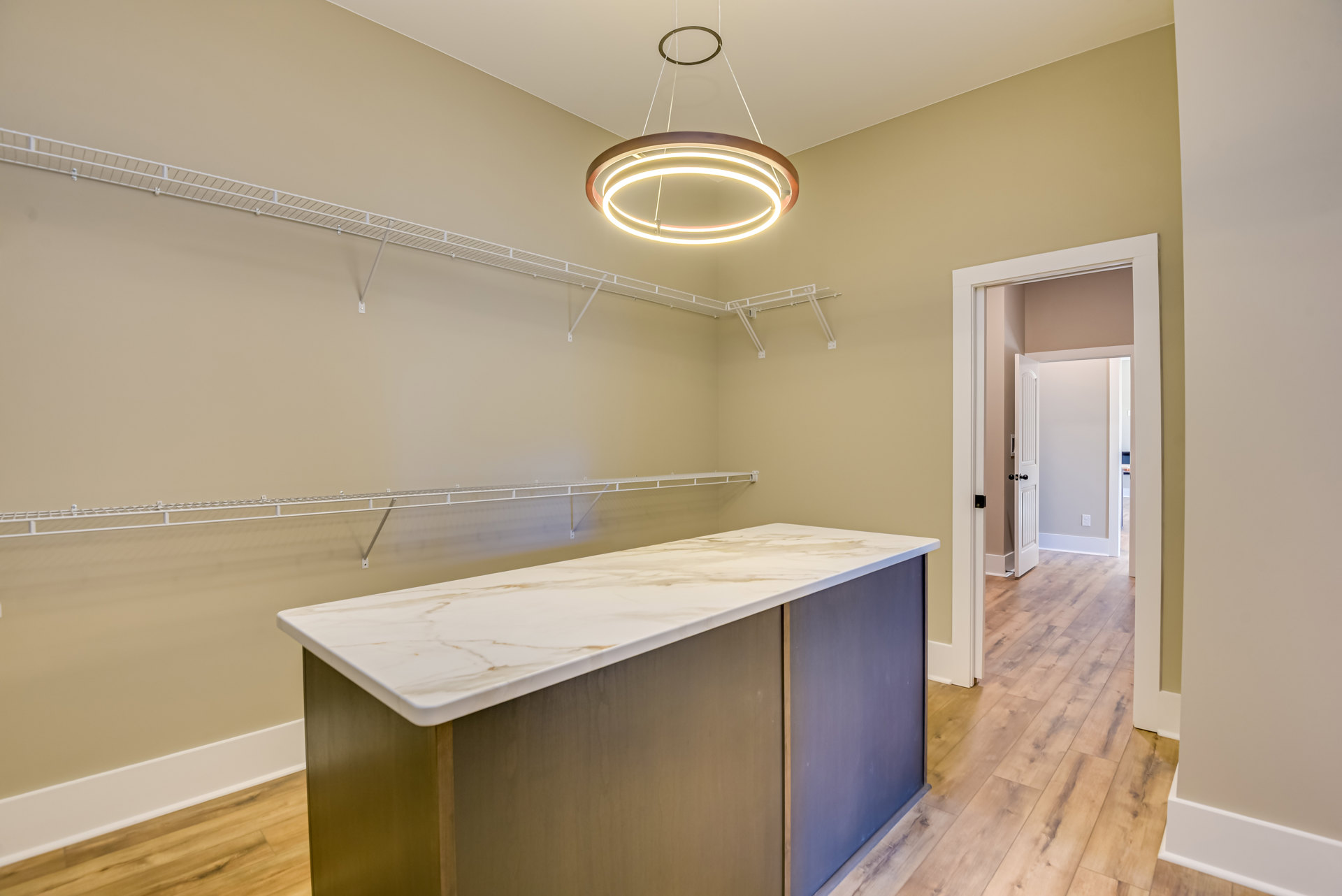 Marble countertop with built-in sink, open shelving, black cabinet hardware, pendant light fixture, tiled backsplash, and wood flooring in a modern kitchen or bathroom.