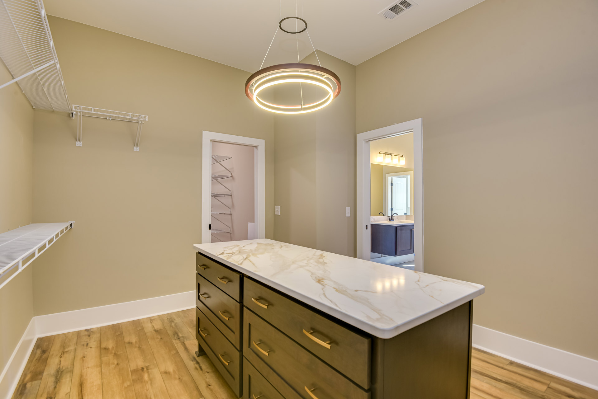 Marble kitchen island with built-in sink, white cabinetry, pendant light overhead, and tiled backsplash