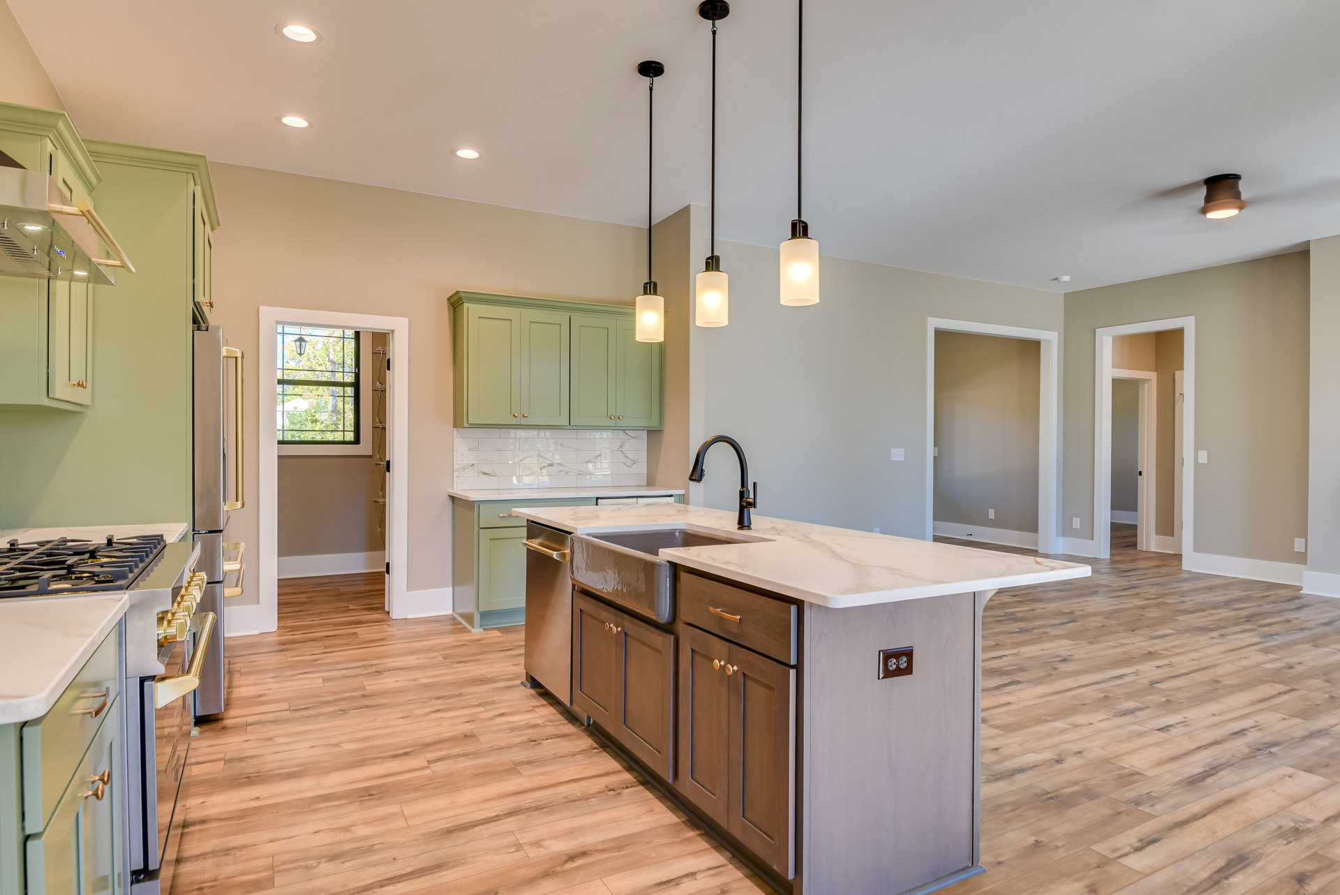 Open kitchen with wood flooring, central island featuring a built-in sink and faucet, white cabinetry, stone countertops, and recessed lighting above