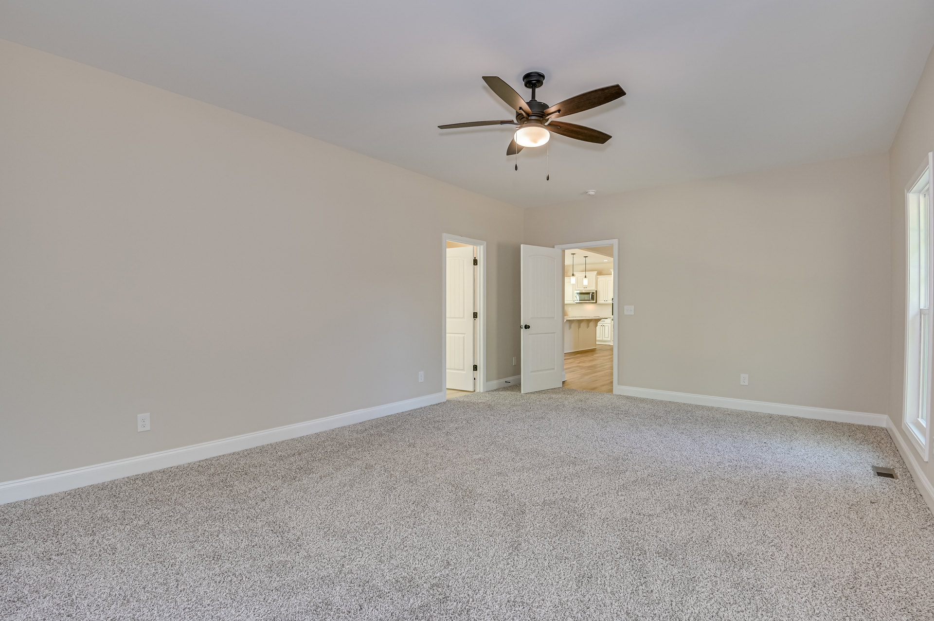 Carpeted room with white walls, white door featuring black hinge and black door knob, ceiling fan with integrated light, black ceiling light fixture, white crown molding