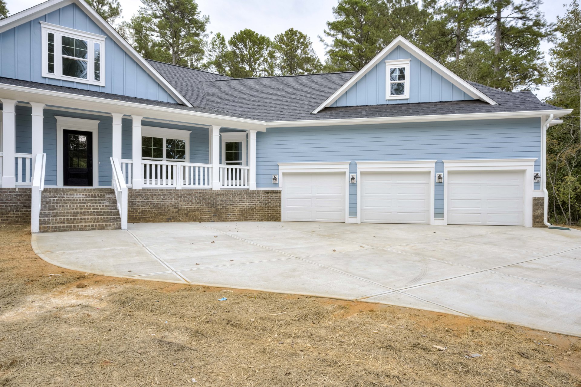 Two-story house with blue siding, white garage door, covered porch, concrete driveway, grassy yard, and exterior lighting.