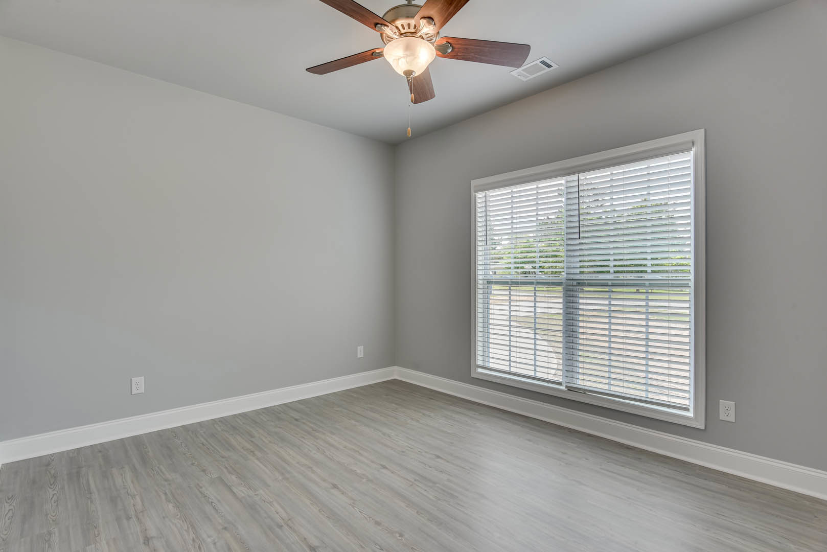 Wood flooring room with white walls, ceiling fan with light fixture, window with horizontal blinds, crown molding along ceiling edges