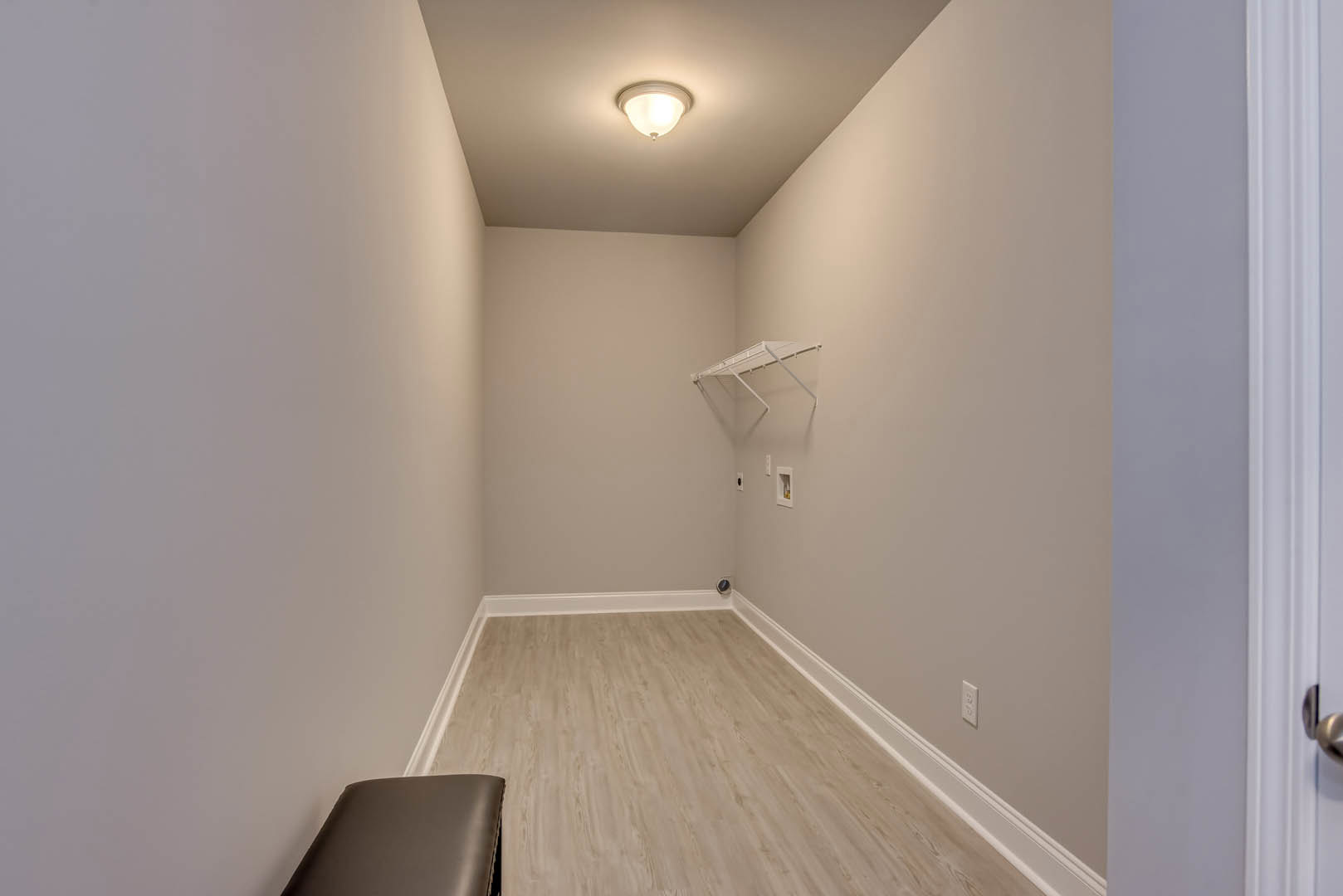 Hallway with wood flooring, white baseboards, built-in bench, ceiling light fixture, and white shelf with metal frame