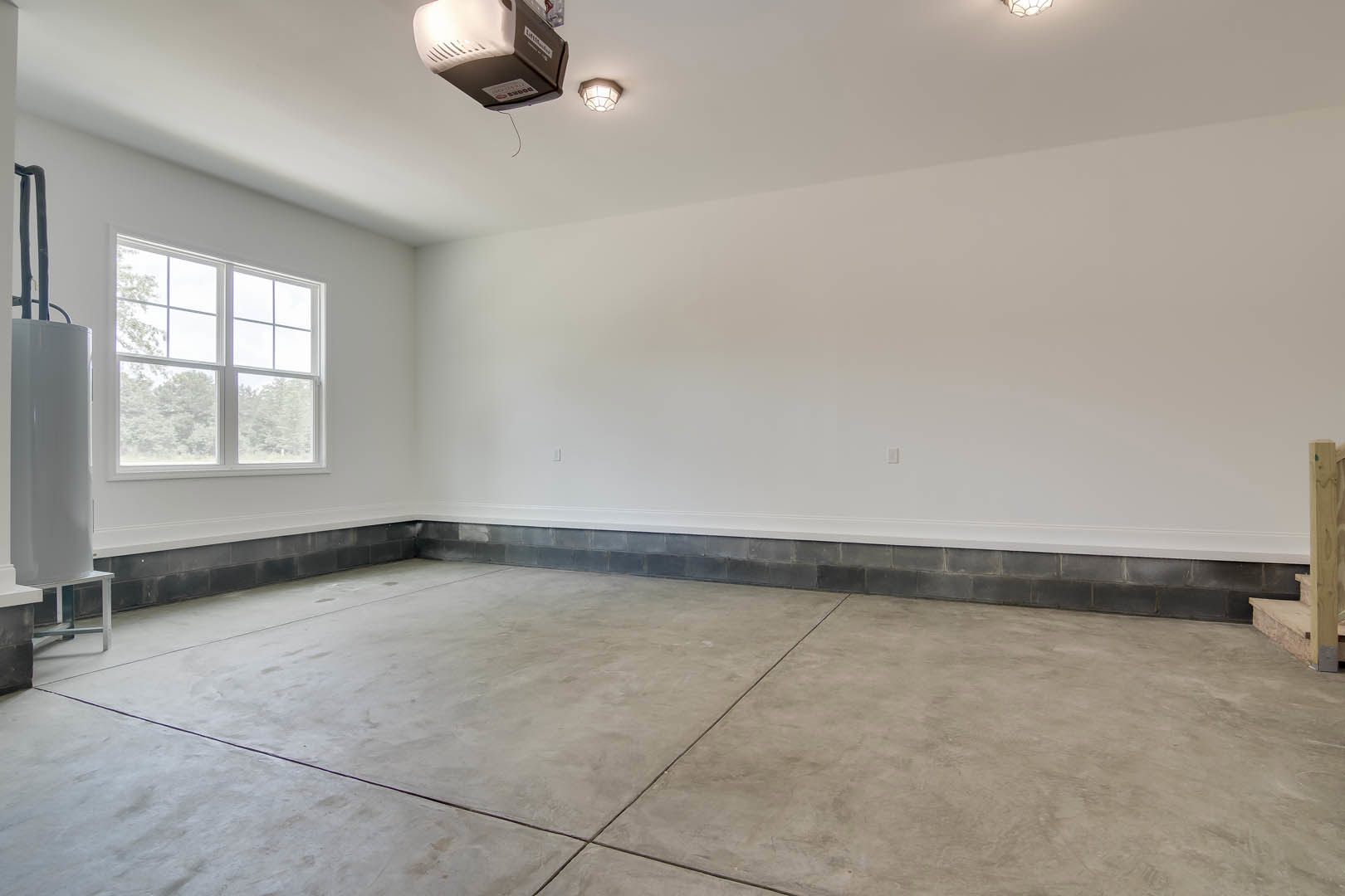 Concrete floor with subtle texture, ceiling-mounted light fixture, wall of square windows, wood panel accent, laptop on floor