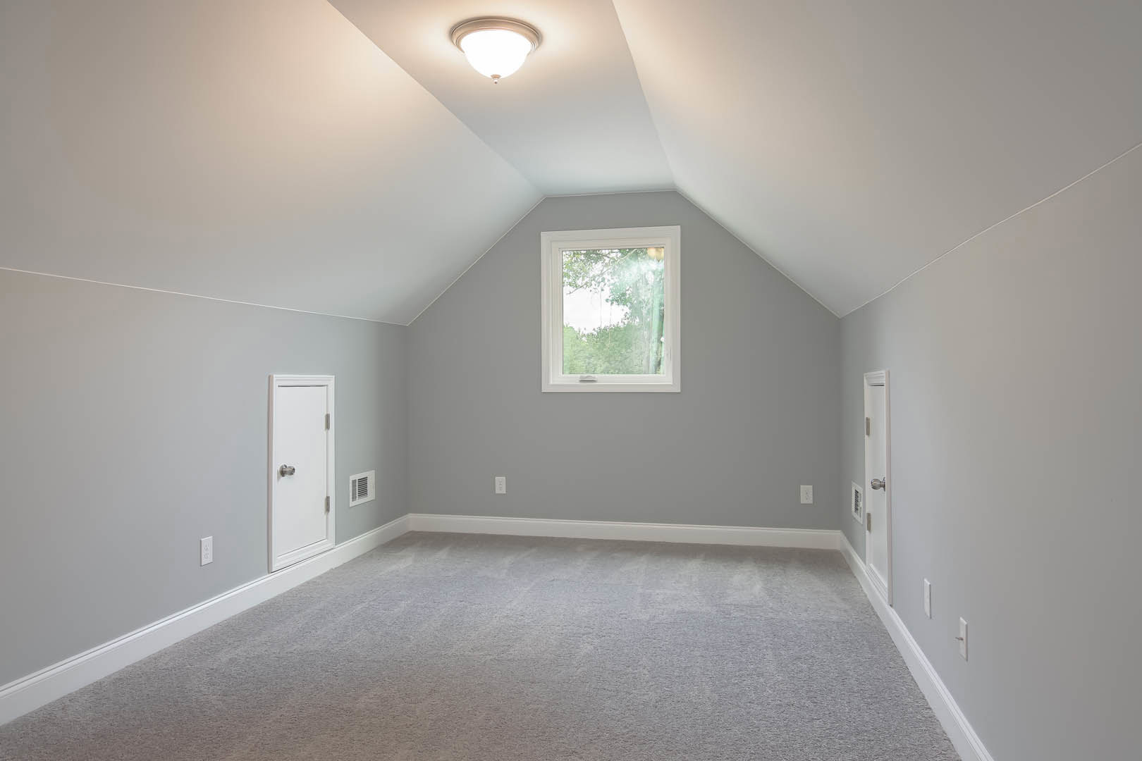 Carpeted room with white walls, white-framed window, ceiling-mounted light fixture, and a close-up view of a door with a metallic knob.