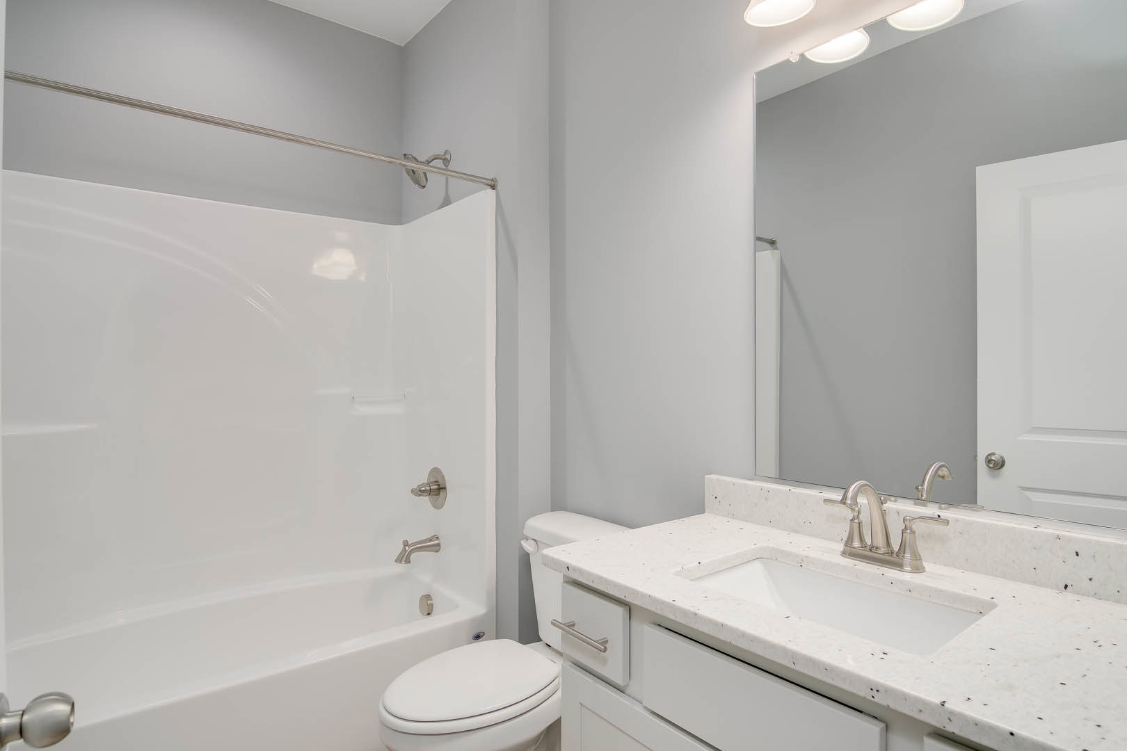 Modern bathroom featuring a white porcelain sink with chrome faucet, white toilet, glass-enclosed shower with tiled walls, and light-colored floor tiles