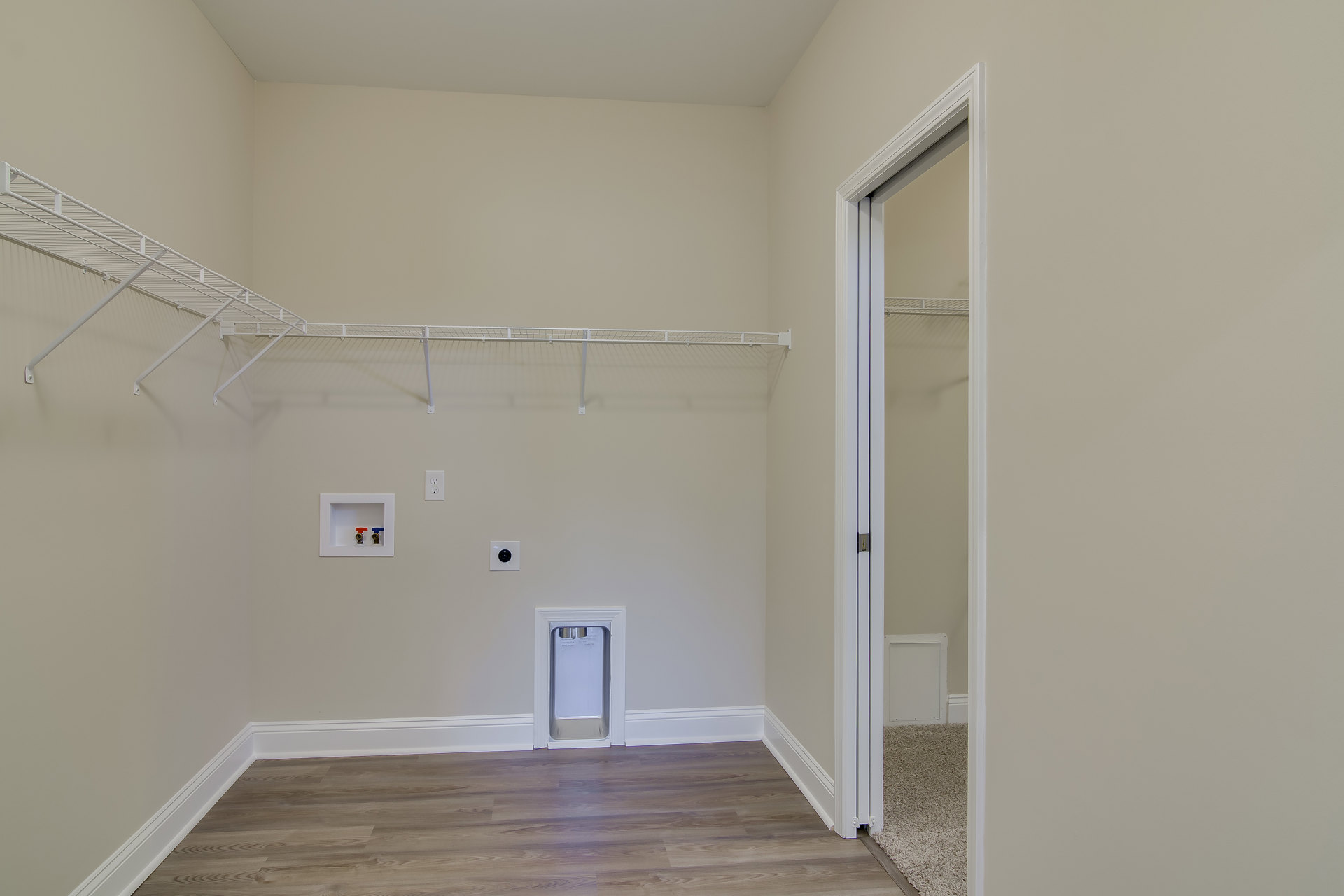Bedroom with wood flooring, white closet doors featuring silver handles, white framed utility access panel, and a white entry door with a chrome handle.
