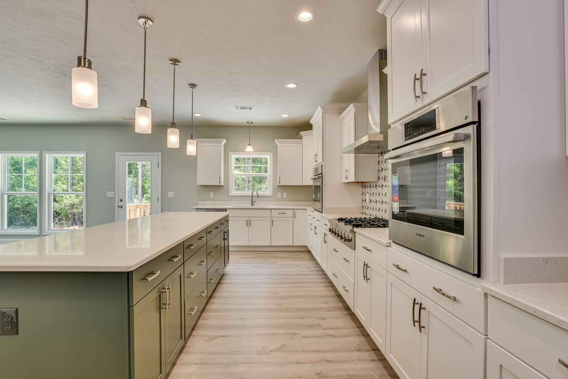 White shaker cabinets, stainless steel oven with glass window, quartz countertops, brushed nickel hardware, tile backsplash, recessed lighting, wood flooring