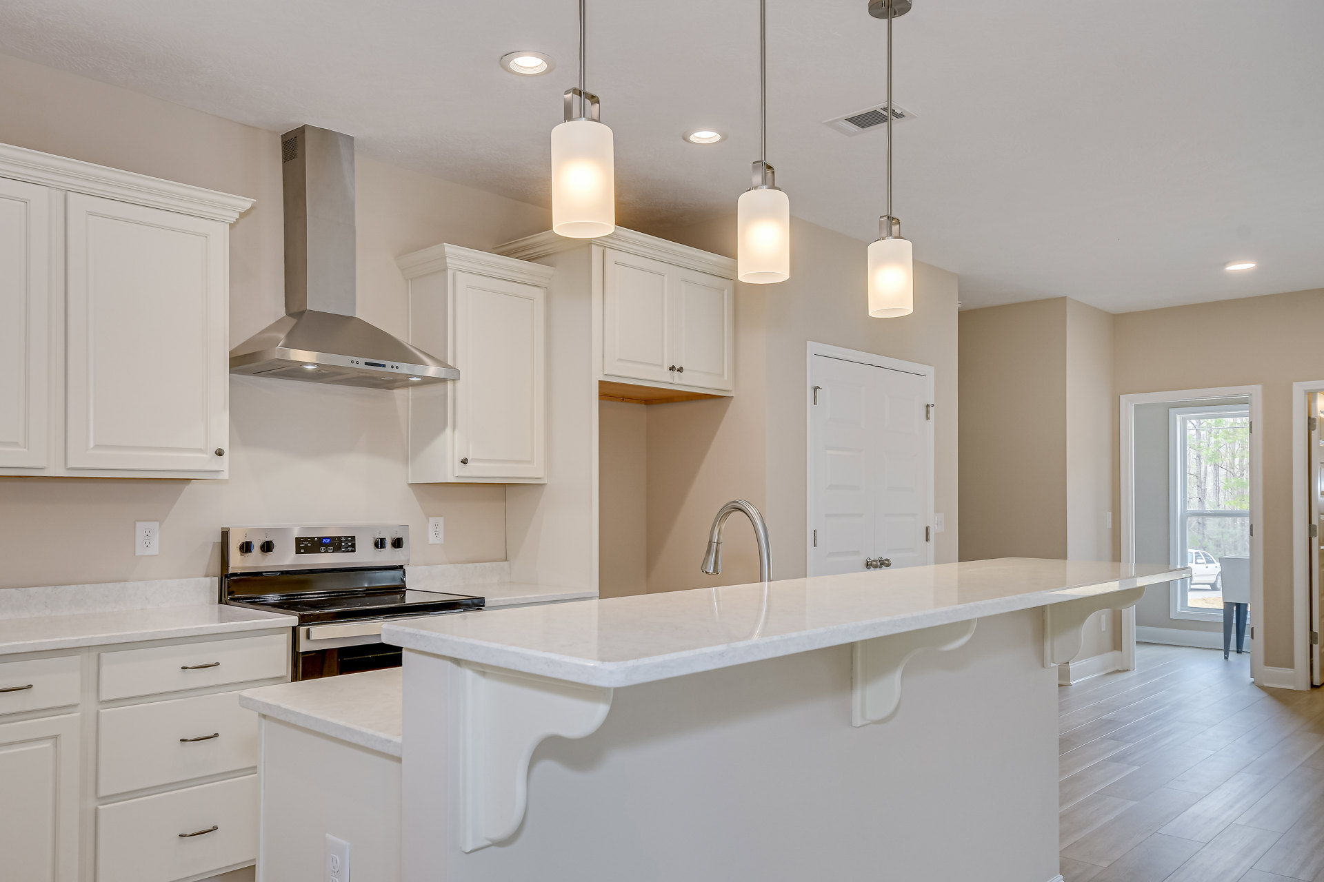 White kitchen with shaker cabinets, quartz countertops, stainless steel faucet, modern light fixture, and silver cabinet handles.