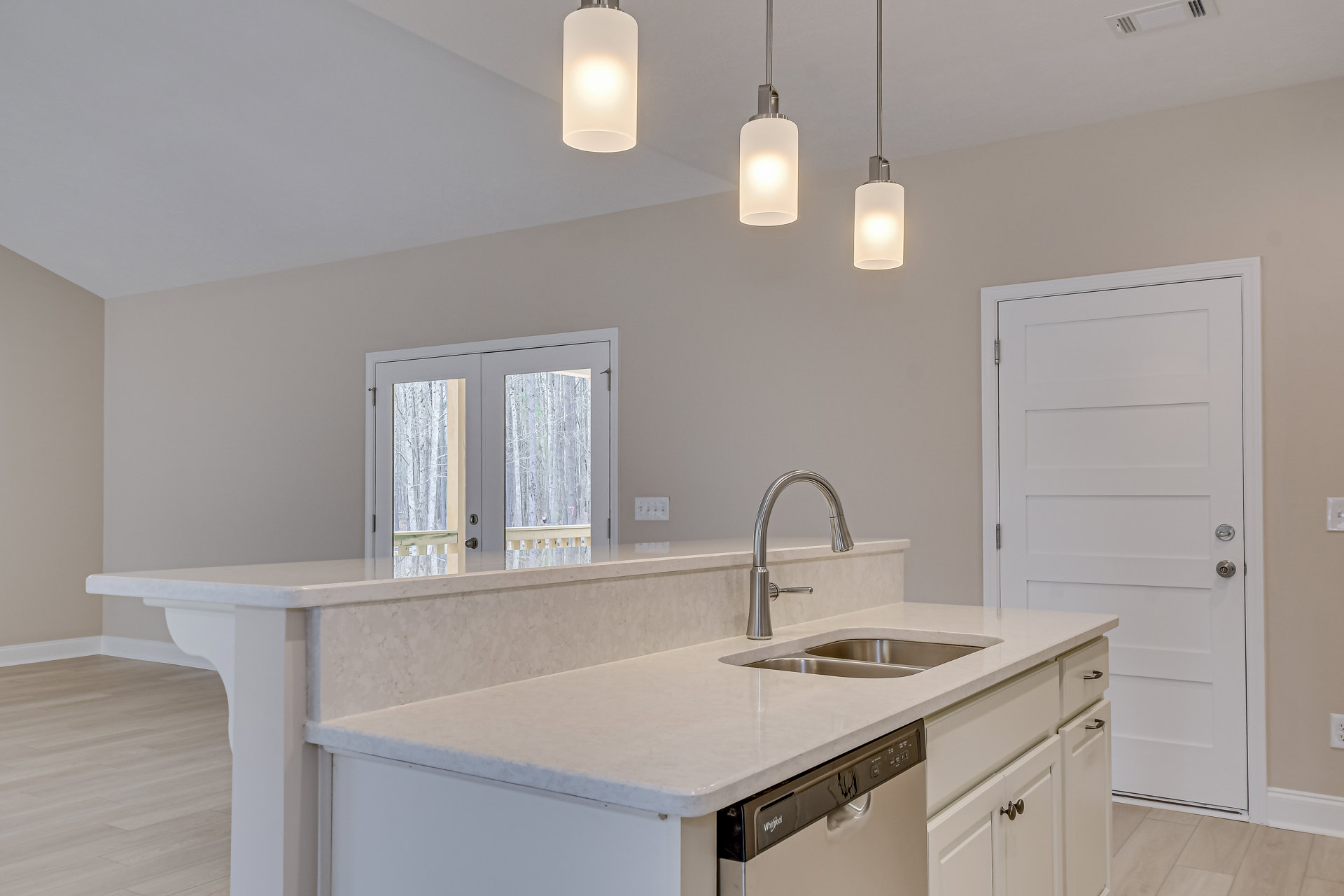 Modern kitchen featuring two stainless steel sinks with chrome faucets, white cabinetry, tile backsplash, stone countertops, double glass-panel doors, and recessed lighting.