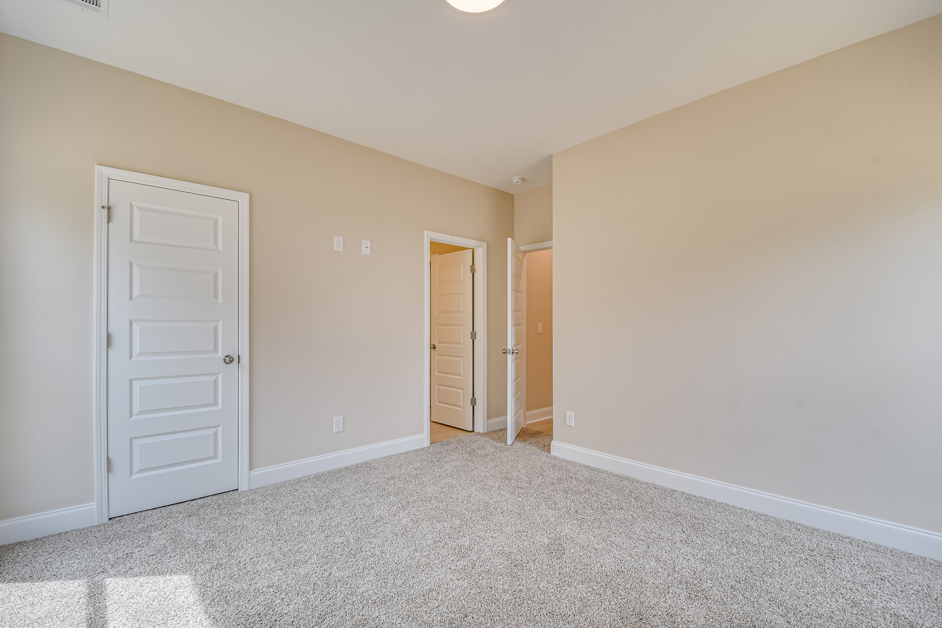 White walls, white door with silver handle, carpeted floor, simple baseboard molding