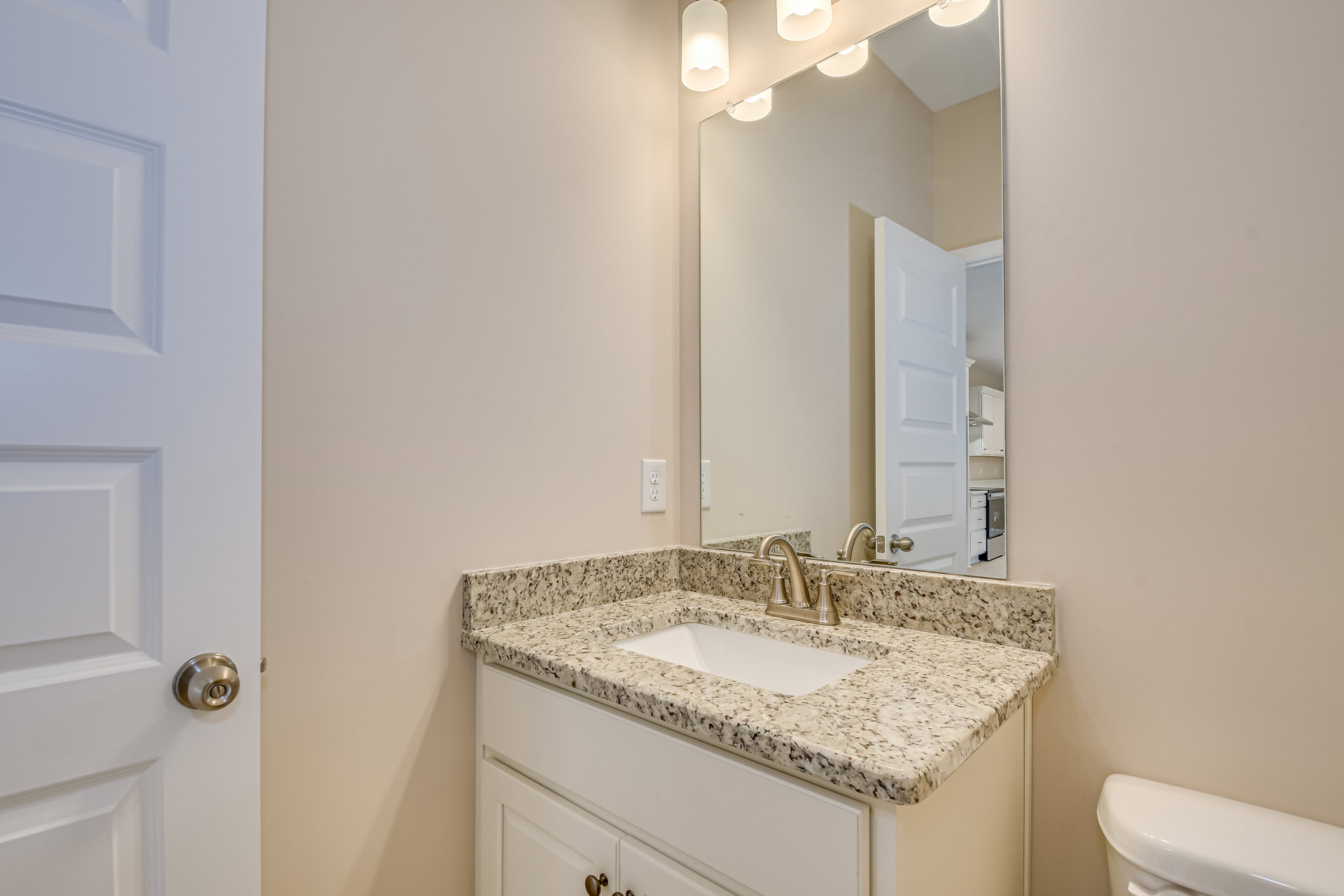 White quartz countertop with undermount sink, chrome faucet, large framed mirror, light gray tile backsplash, and wall-mounted sconce in modern bathroom