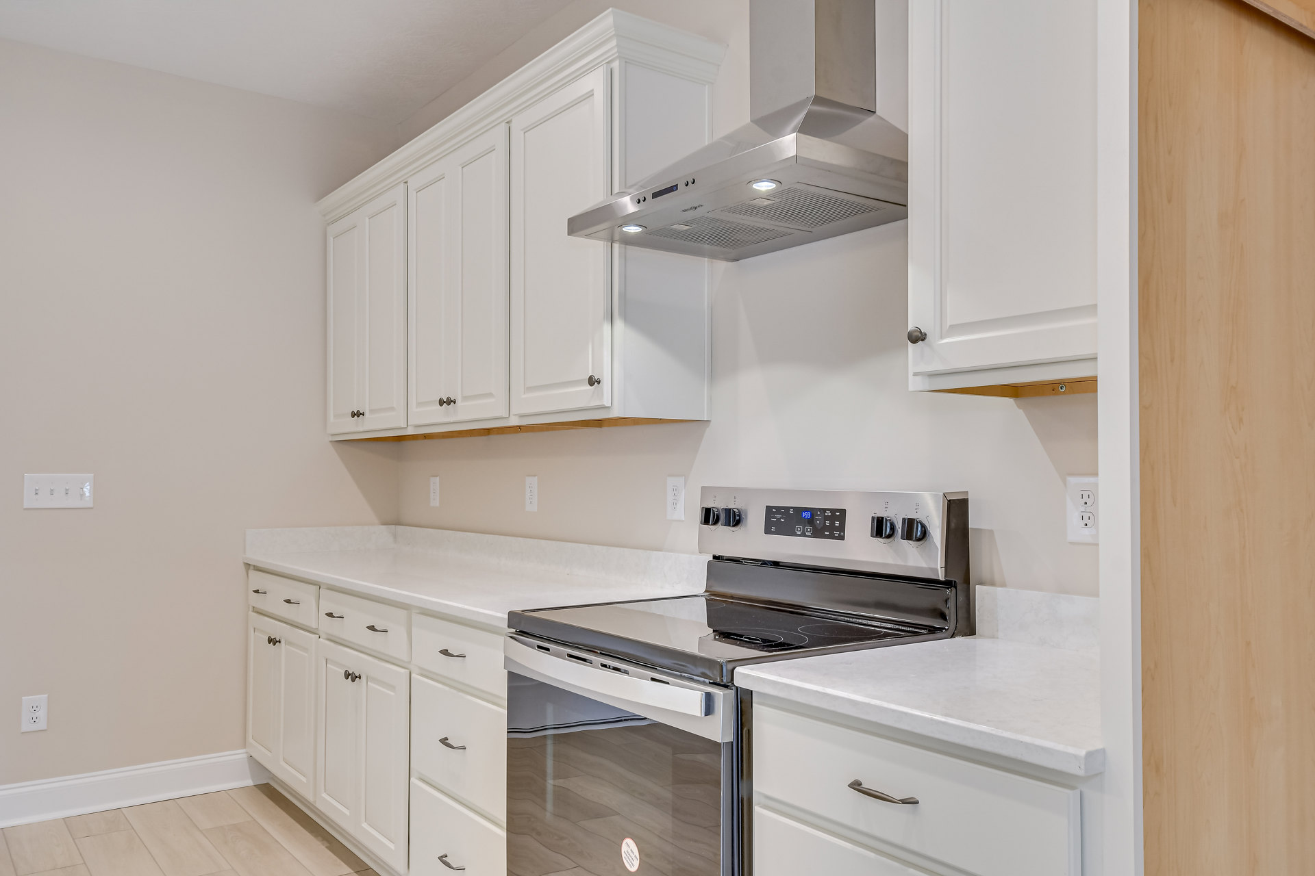 White shaker cabinets, stainless steel range and oven, quartz countertops, subway tile backsplash, wood flooring, open shelving with silver brackets