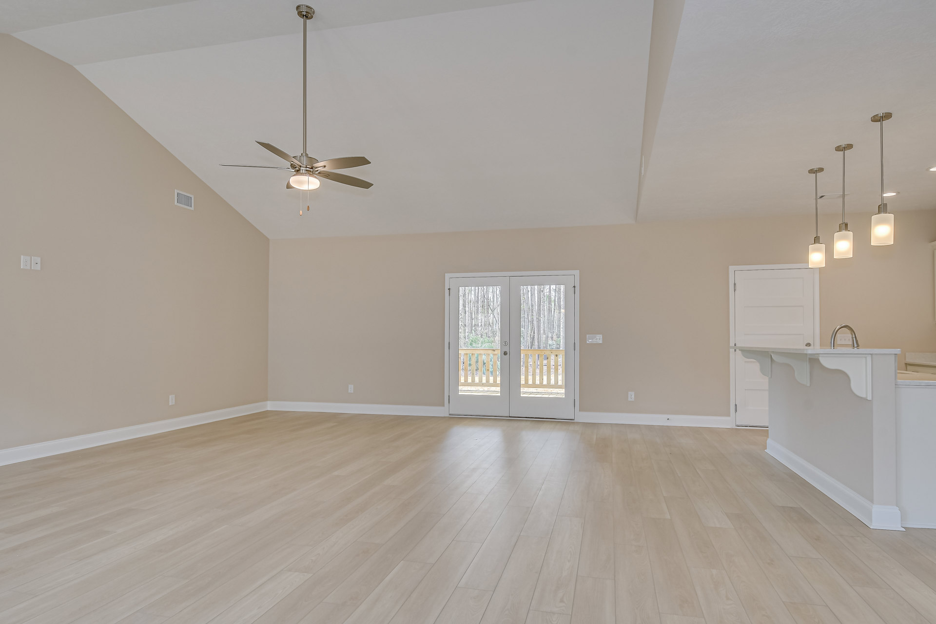 Wood flooring and white walls in a room with a ceiling fan and light fixture, double glass-paneled doors, and a white shade.