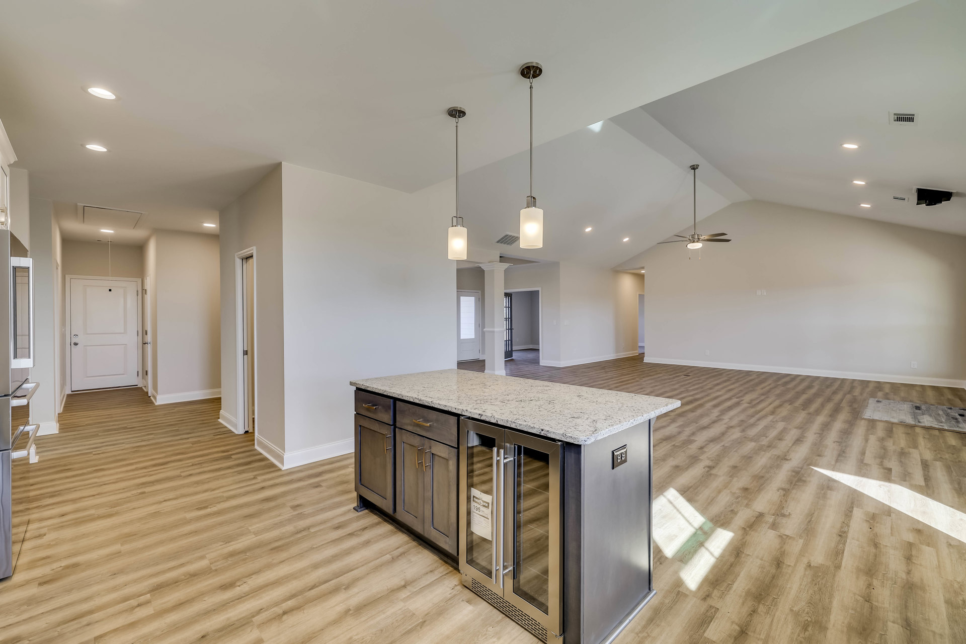 Marble countertop kitchen with wood flooring, white cabinetry, stainless steel refrigerator, and a white door with silver handle