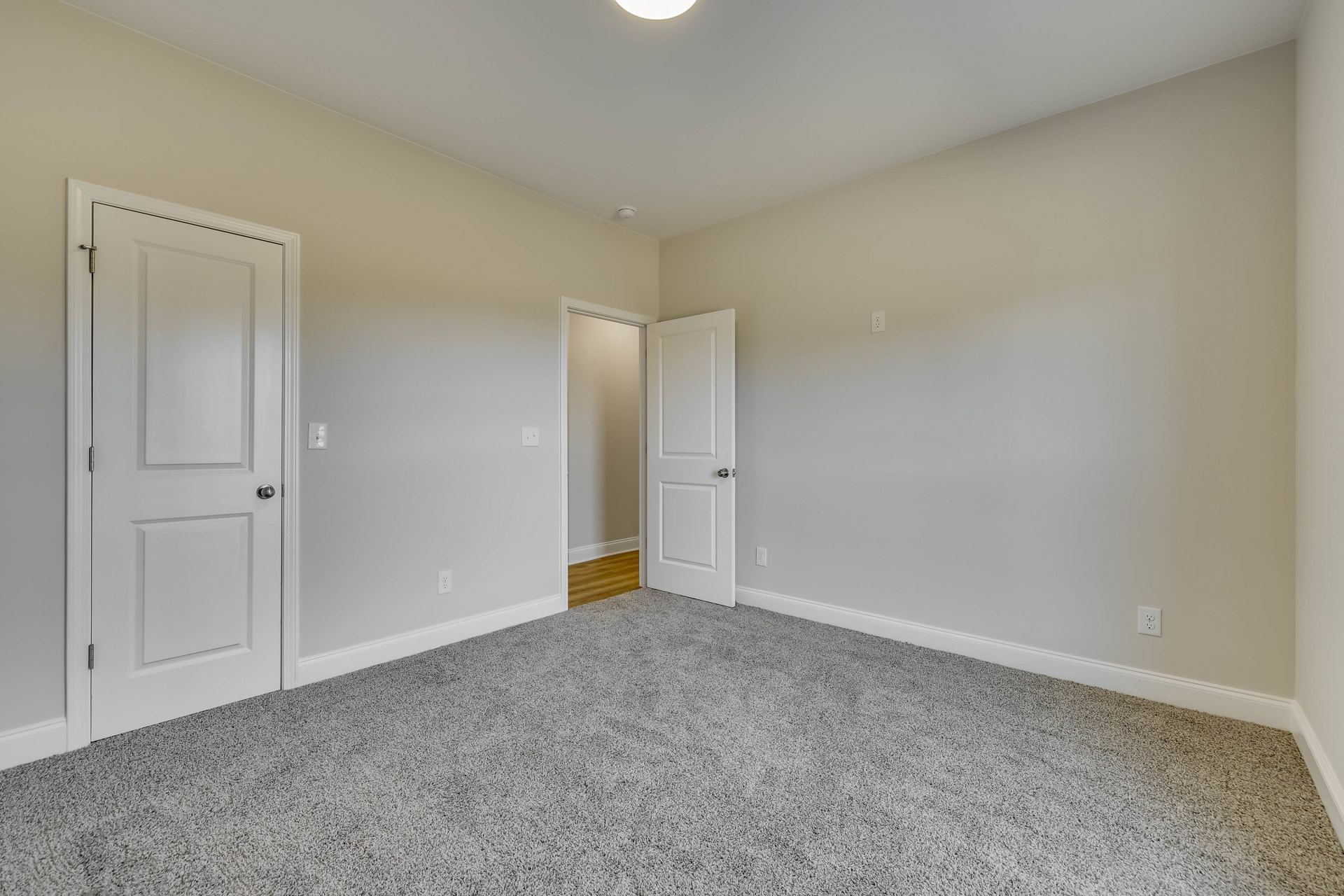 White walls, white door with silver knob, carpeted floor, ceiling with recessed lighting, simple trim and baseboards