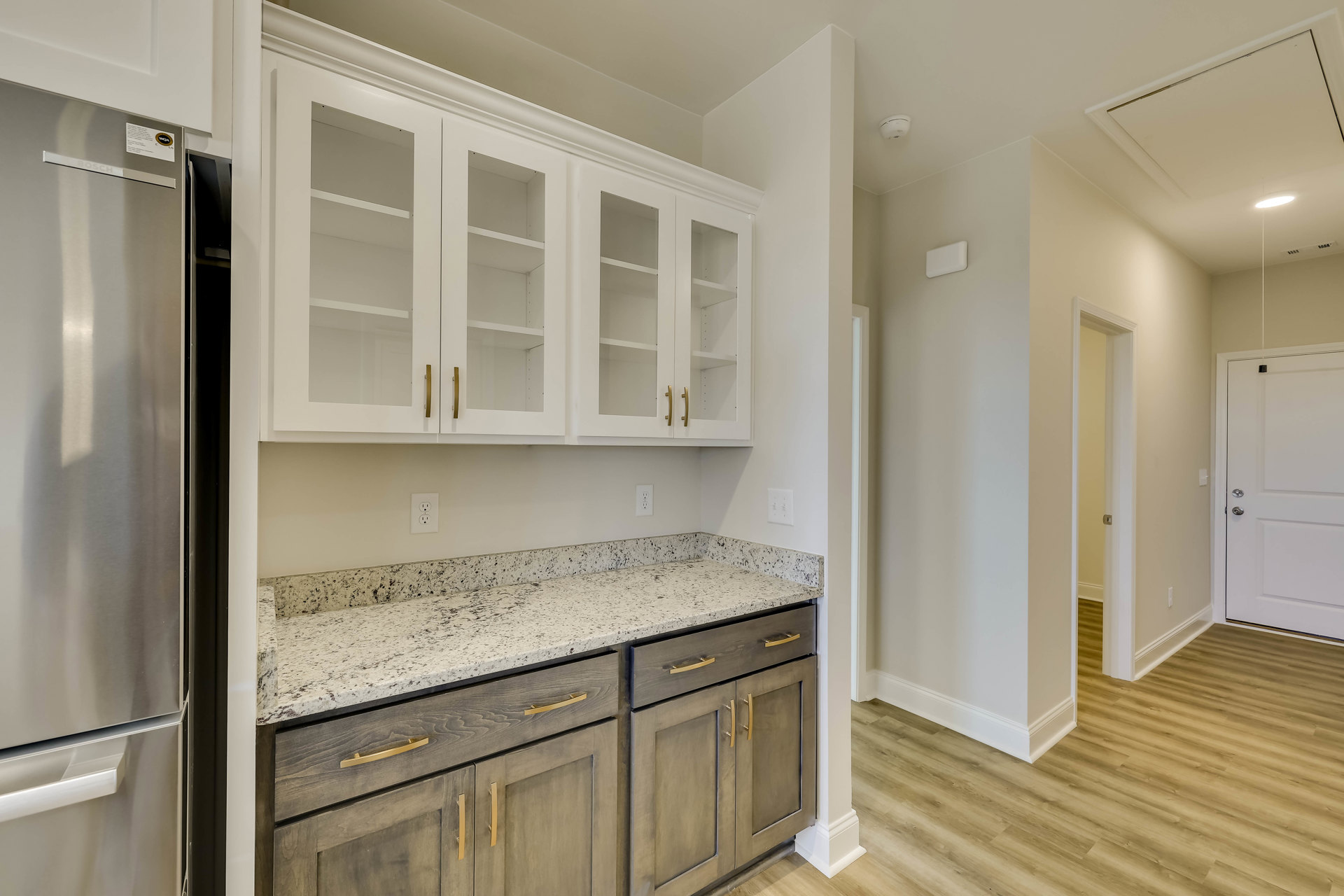 Kitchen featuring white cabinetry, marble countertops, stainless steel sink, tile backsplash, and silver hardware on doors and drawers