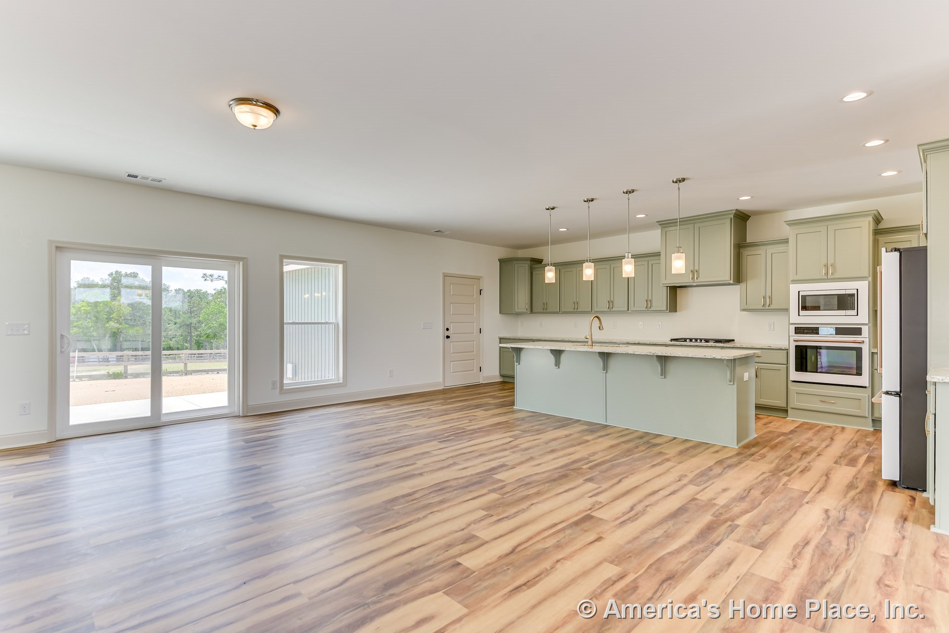 Sage green kitchen cabinetry with full-height upper cabinets, quartz countertops, built-in stainless double wall ovens, wide plank wood-look flooring, large sliding glass door