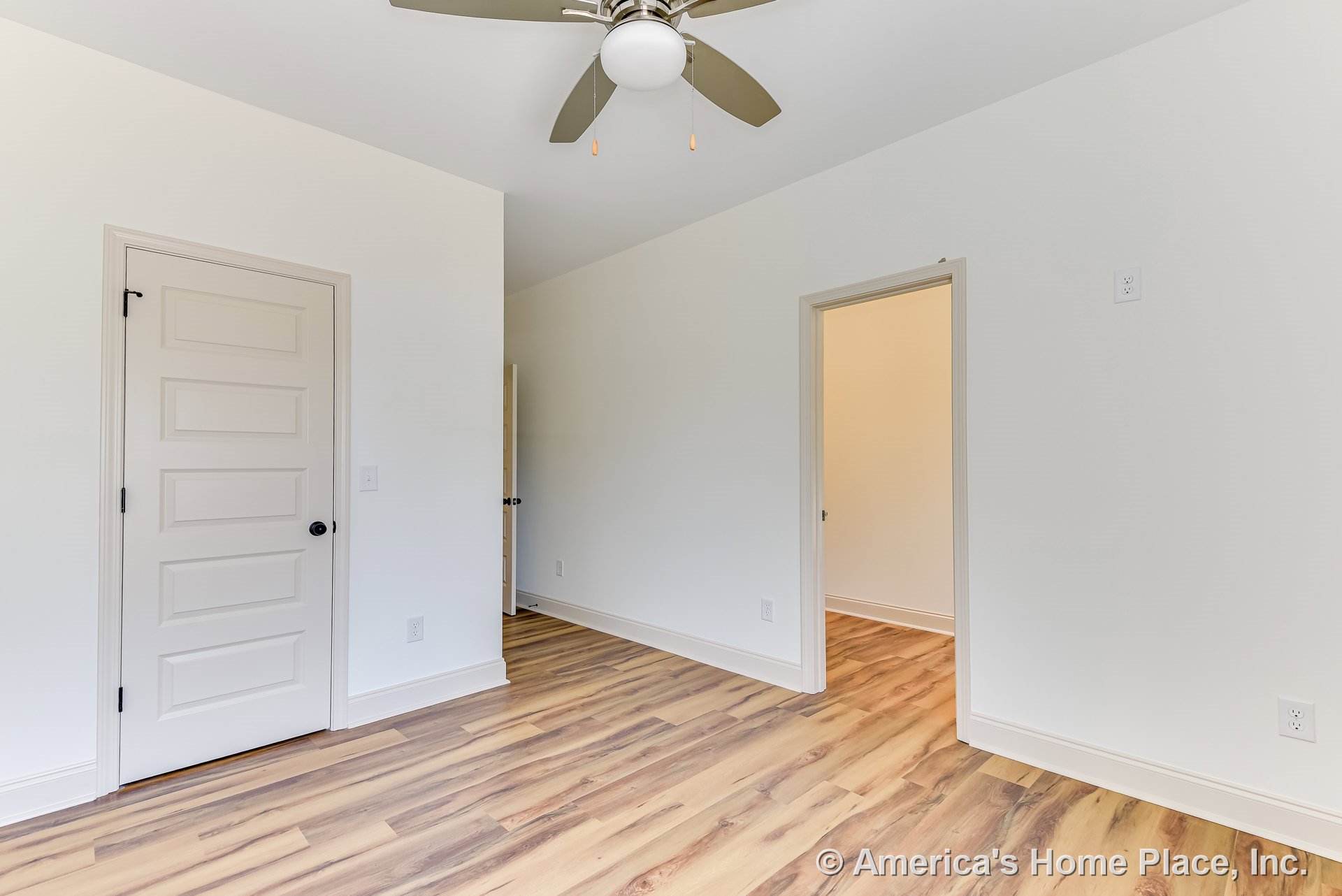 Bedroom with wood-look vinyl plank flooring, neutral painted walls, white paneled closet and entry doors, ceiling fan with integrated light, baseboards and trim, and multiple