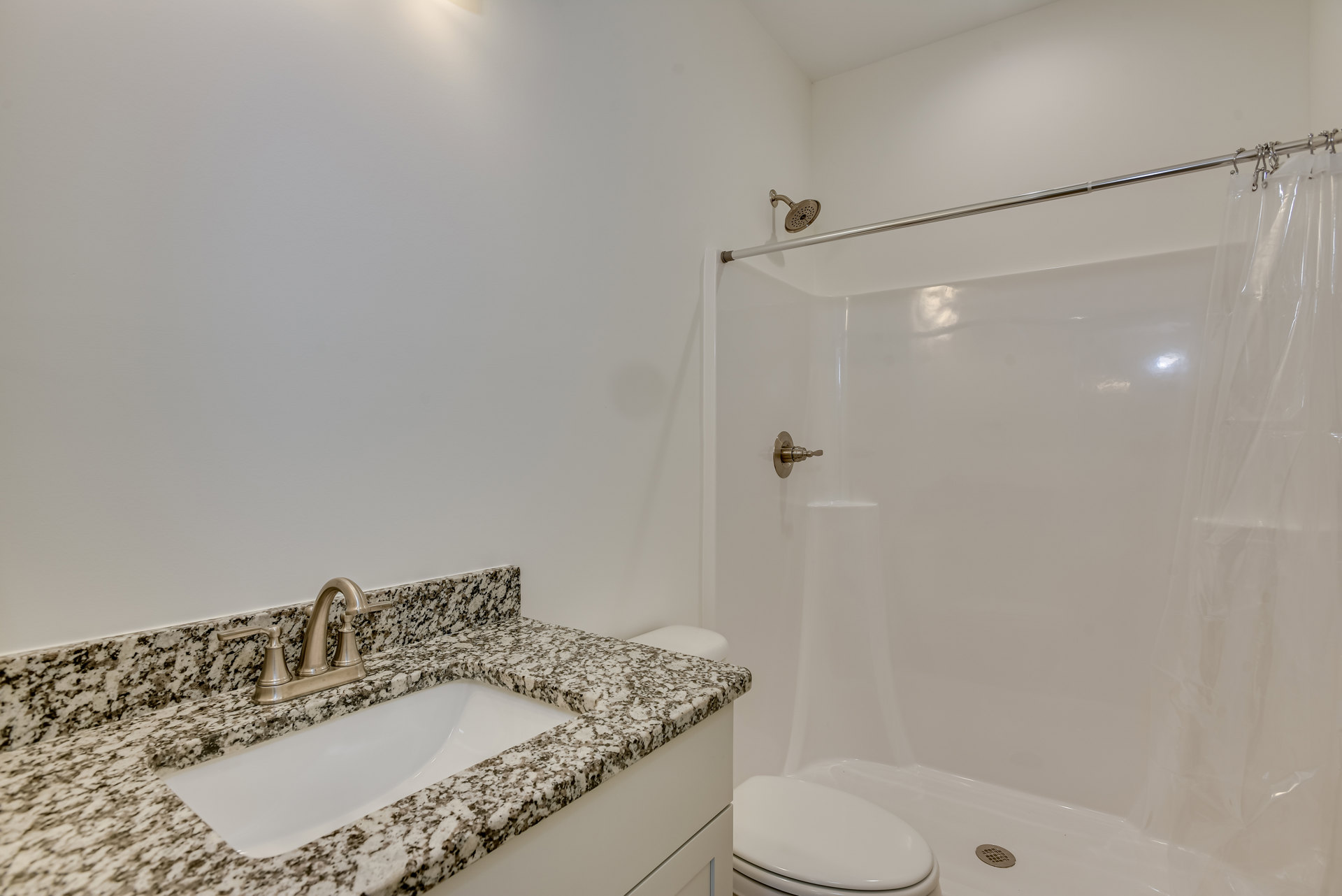 Modern bathroom featuring a white ceramic sink with chrome faucet, glass-enclosed shower with tiled walls, wall-mounted mirror, and neutral tile flooring