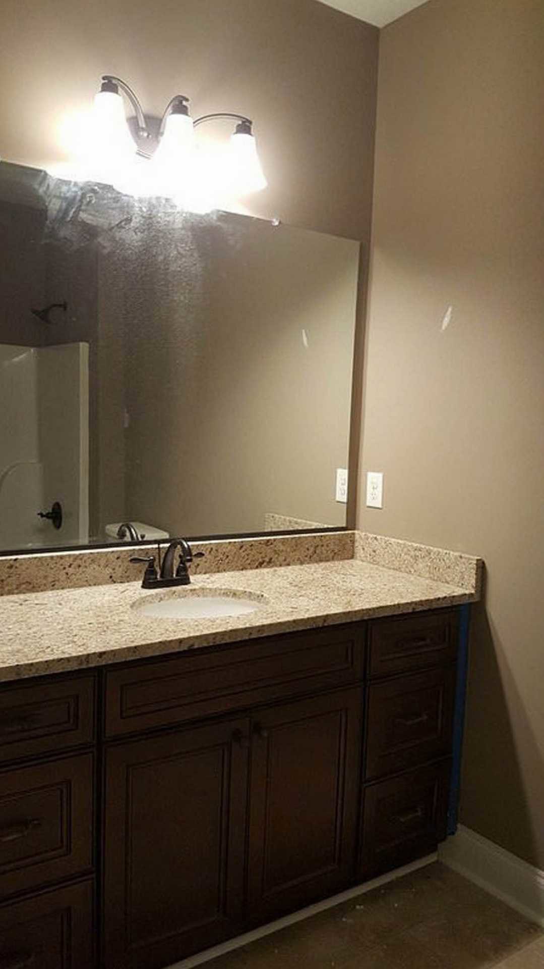 Modern bathroom featuring a large framed mirror above a white countertop with chrome faucet, light gray tile backsplash, and sleek cabinetry.
