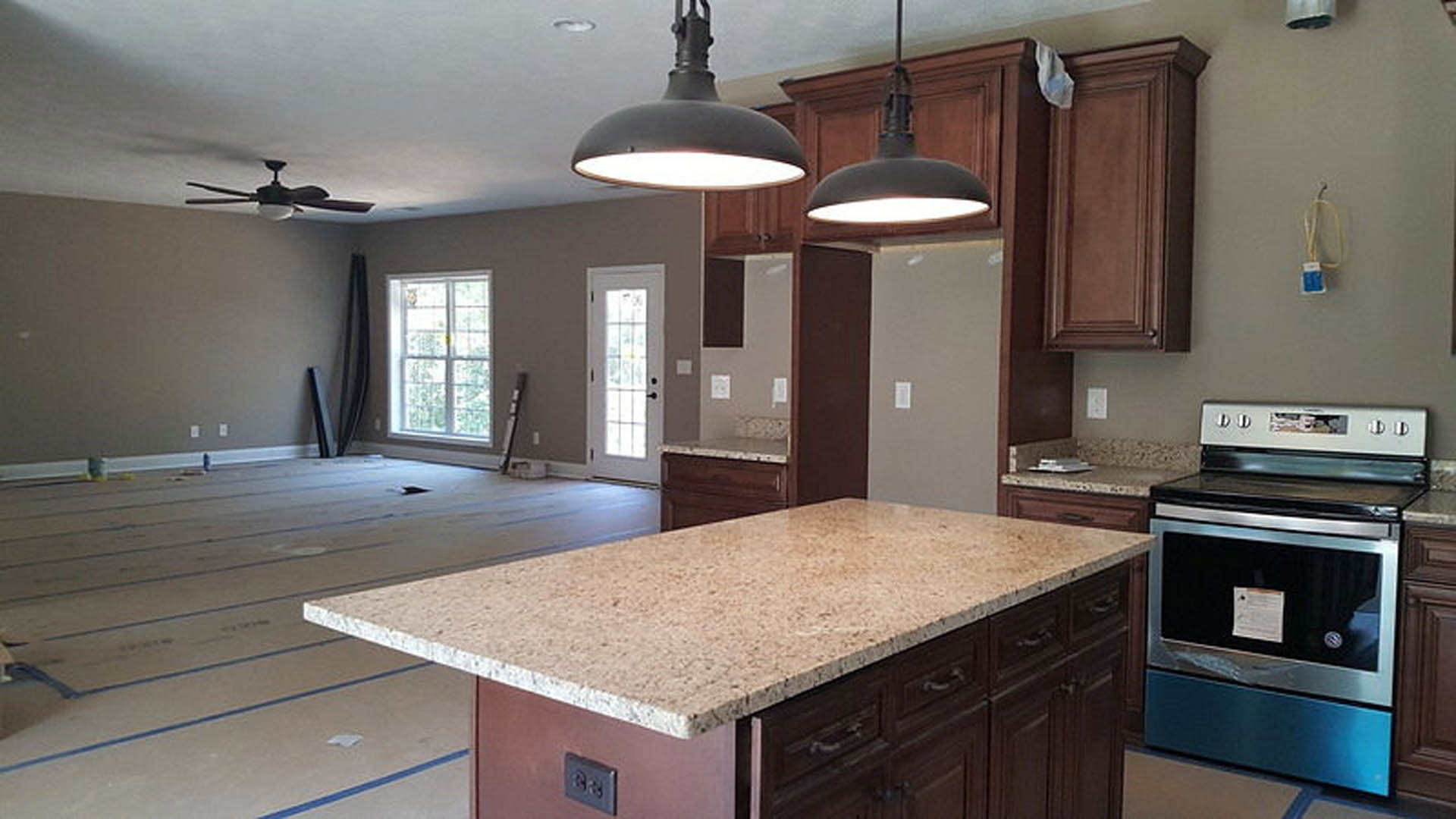 Spacious kitchen featuring a large central island with quartz countertop, stainless steel stove, white cabinetry, pendant light fixture, and window above the sink