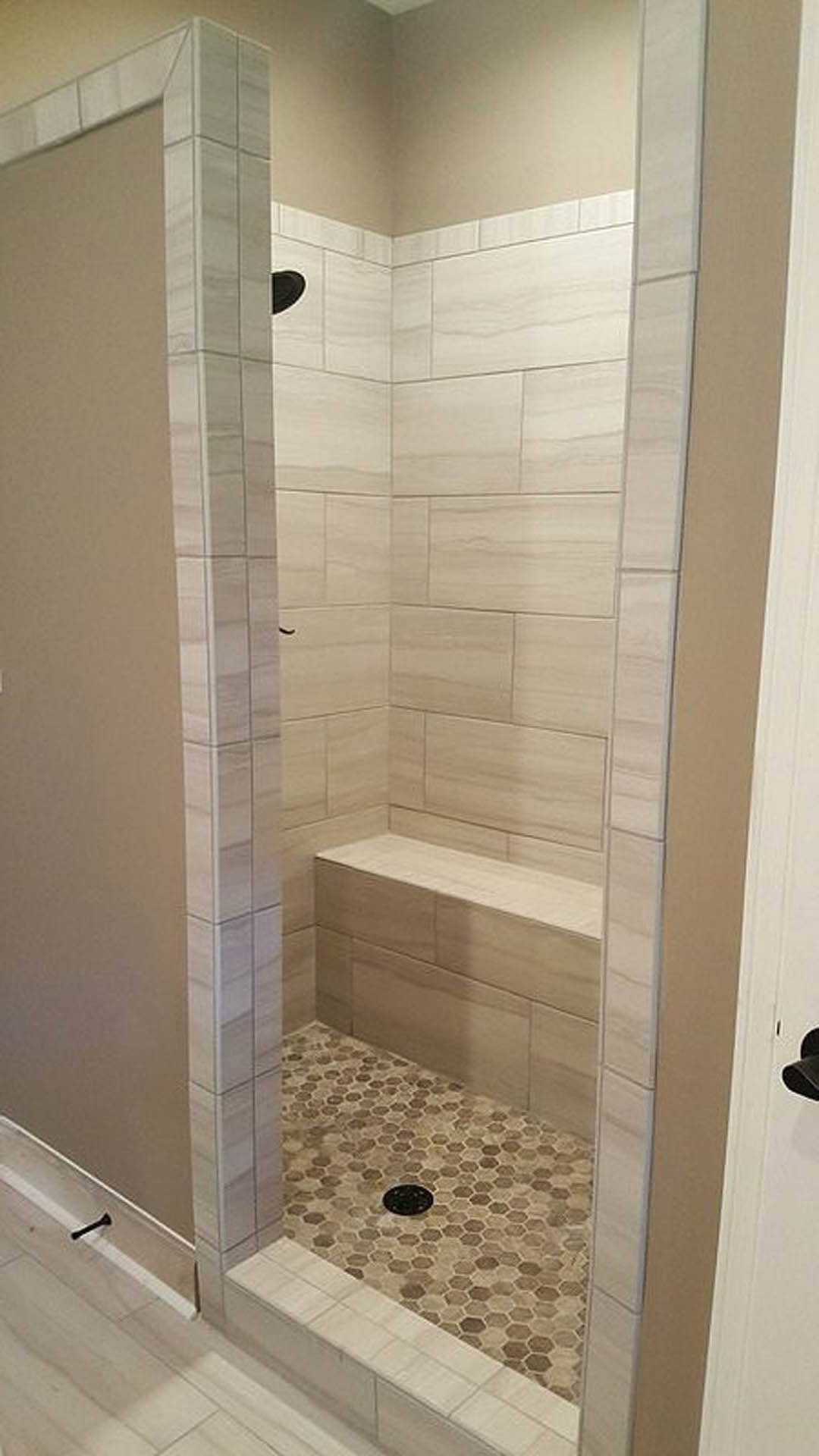 Walk-in shower with marble tile walls, built-in bench, glass enclosure, and tile flooring