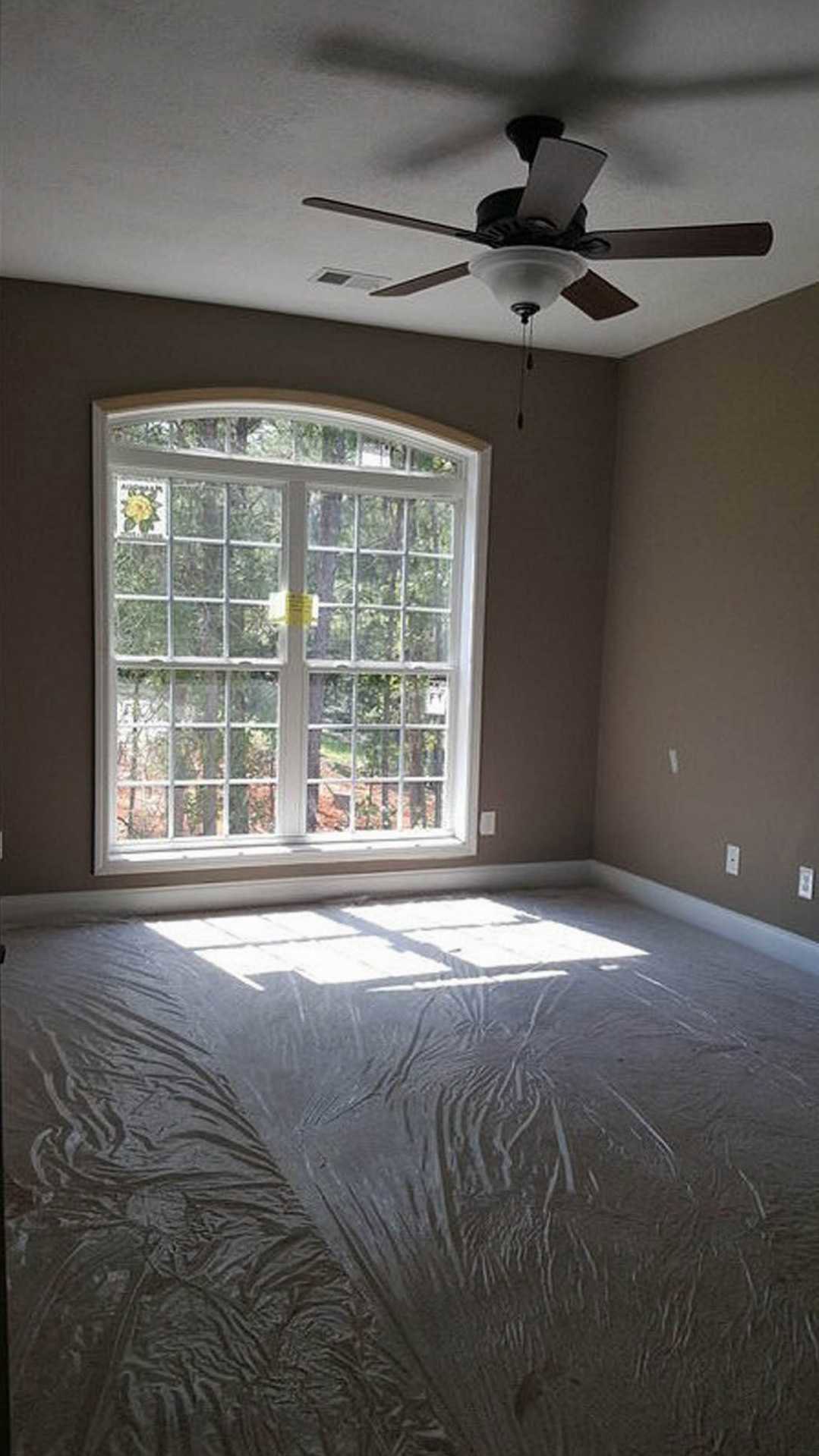 Bright room with plaster walls, large window, and ceiling fan with integrated light fixture