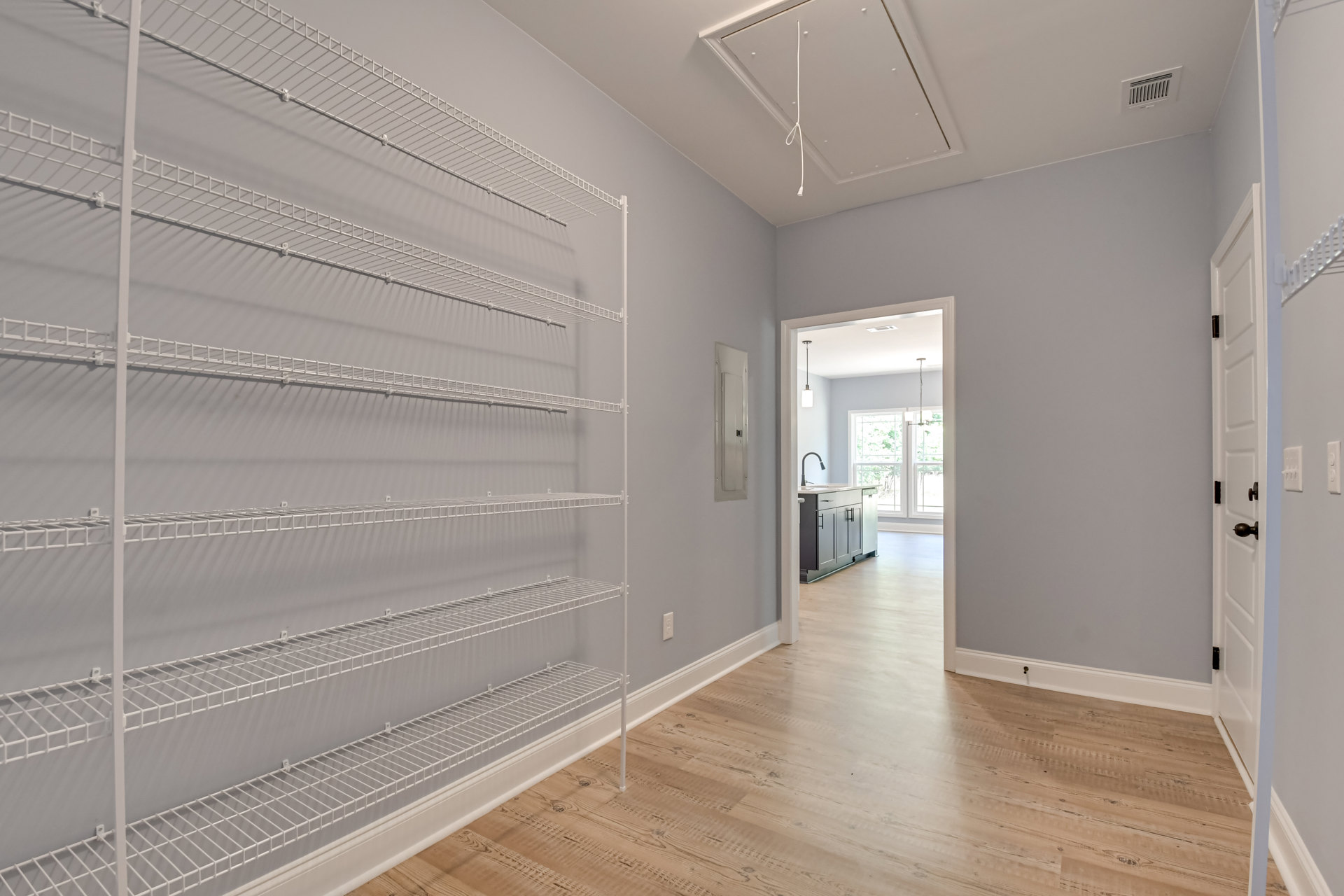 Wood flooring and white built-in shelving along a plaster wall in a bright indoor room.