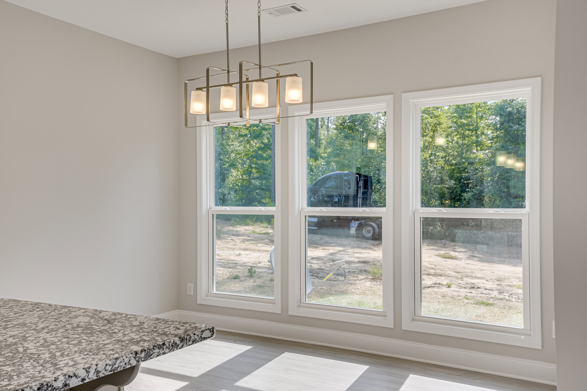 Dining area with wood table, large windows with white blinds, neutral walls, and modern chandelier overhead