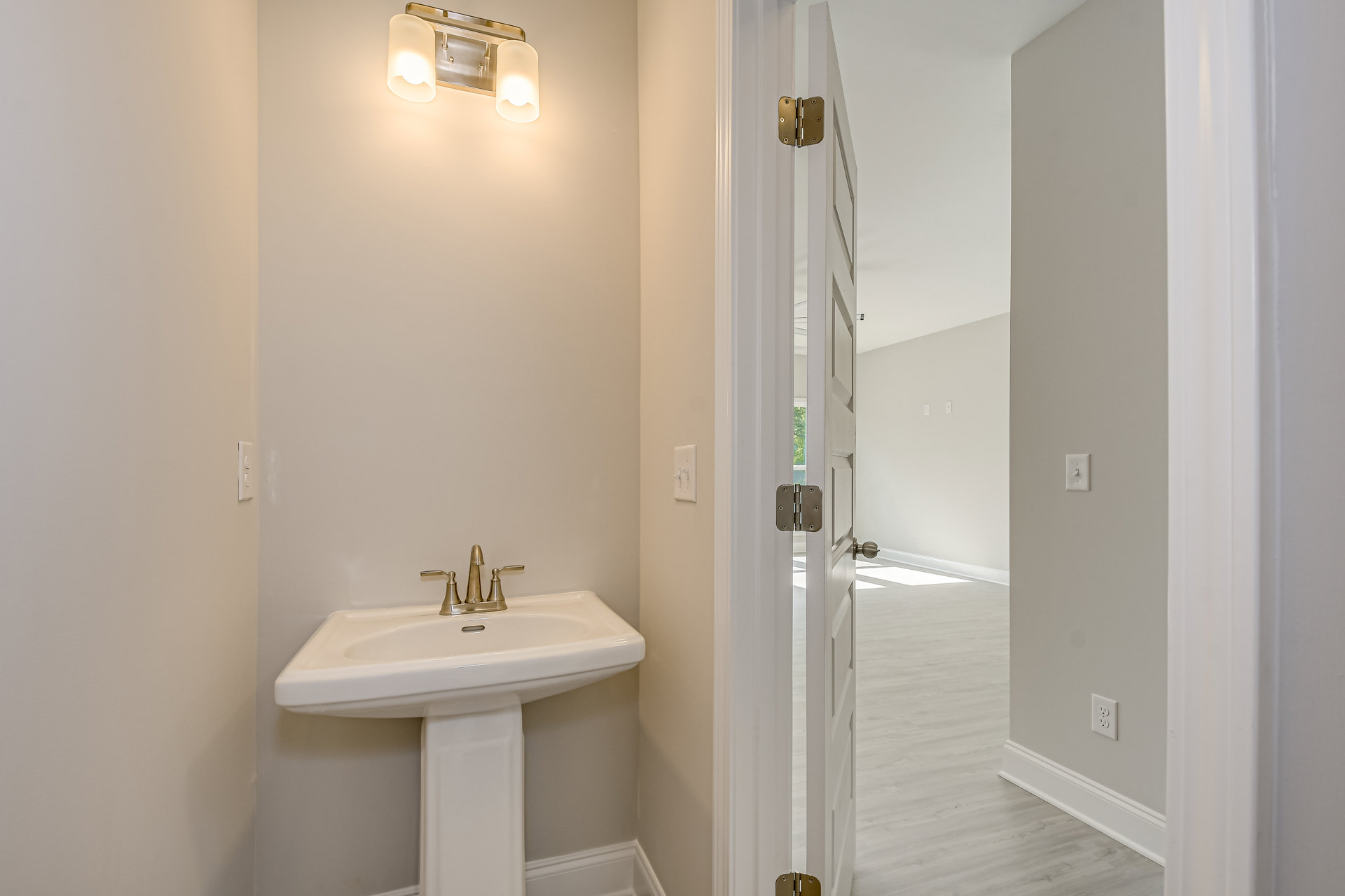 White tile bathroom with chrome faucet, undermount sink, double light fixture above mirror, and paneled door with visible hinge