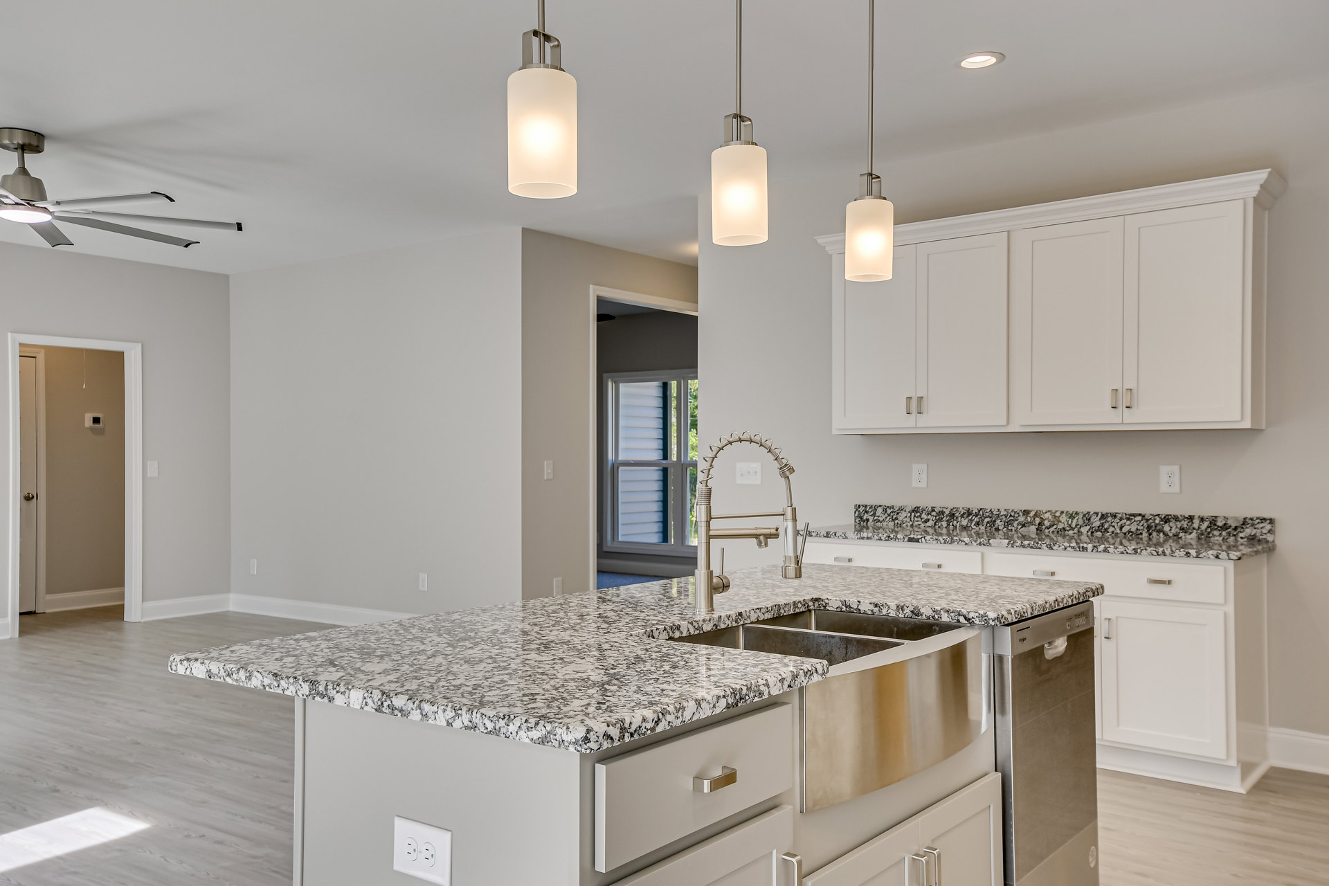 Granite countertop kitchen with undermount sink, stainless steel faucet, white cabinets with silver handles, tile backsplash, and built-in appliances