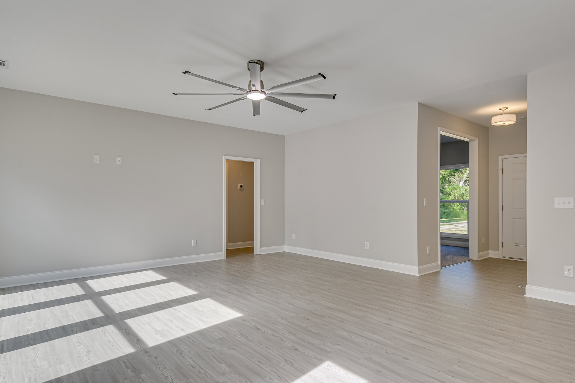 Ceiling fan with light fixture, wood plank flooring, white walls, white door with metal hinge, minimalist interior design