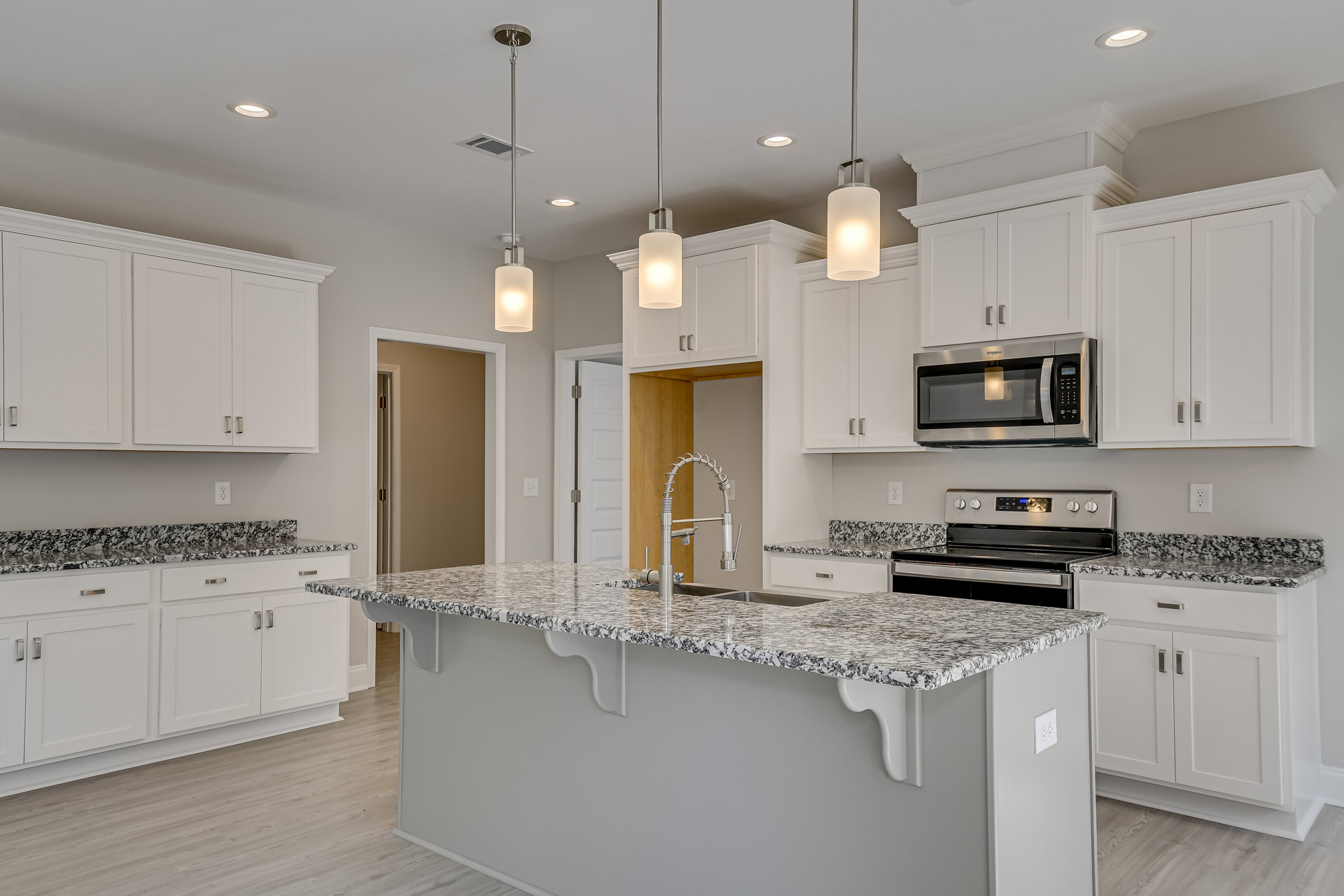 Marble countertop kitchen with white cabinetry, stainless steel appliances including oven and microwave, modern sink and faucet, and wall-mounted light fixture