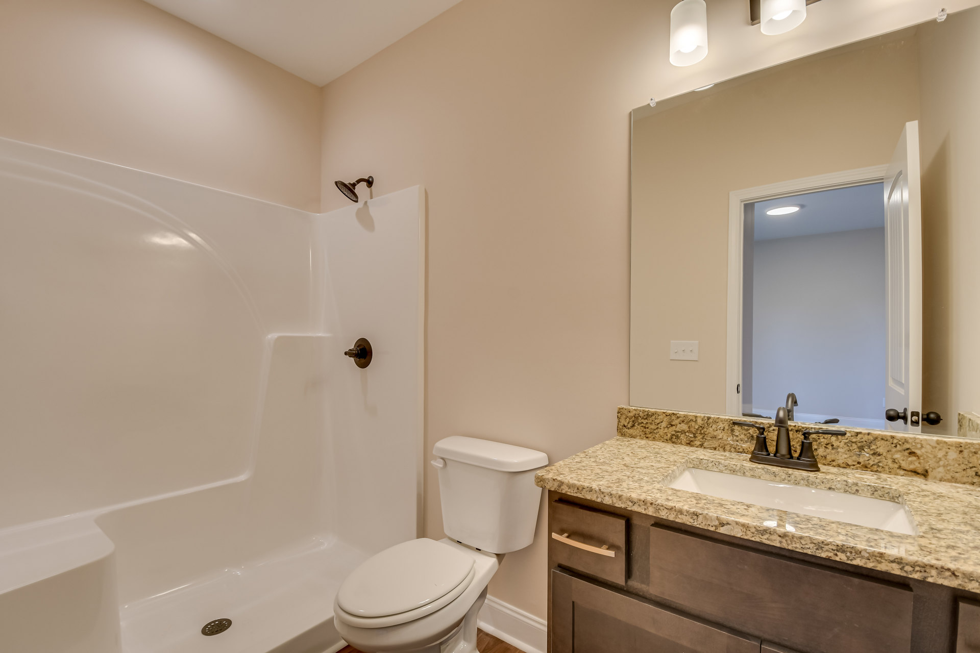White tile bathroom featuring a wall-mounted sink, modern toilet with chrome handle, white bathtub with overhead shower, and neutral painted walls.