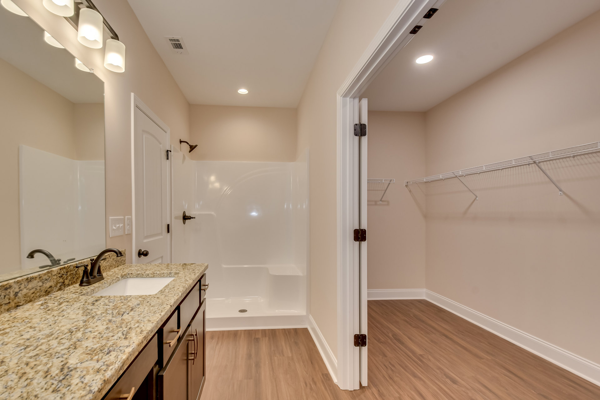Bathroom with marble countertop, undermount sink, chrome faucet, glass-enclosed shower, tile flooring, and recessed lighting