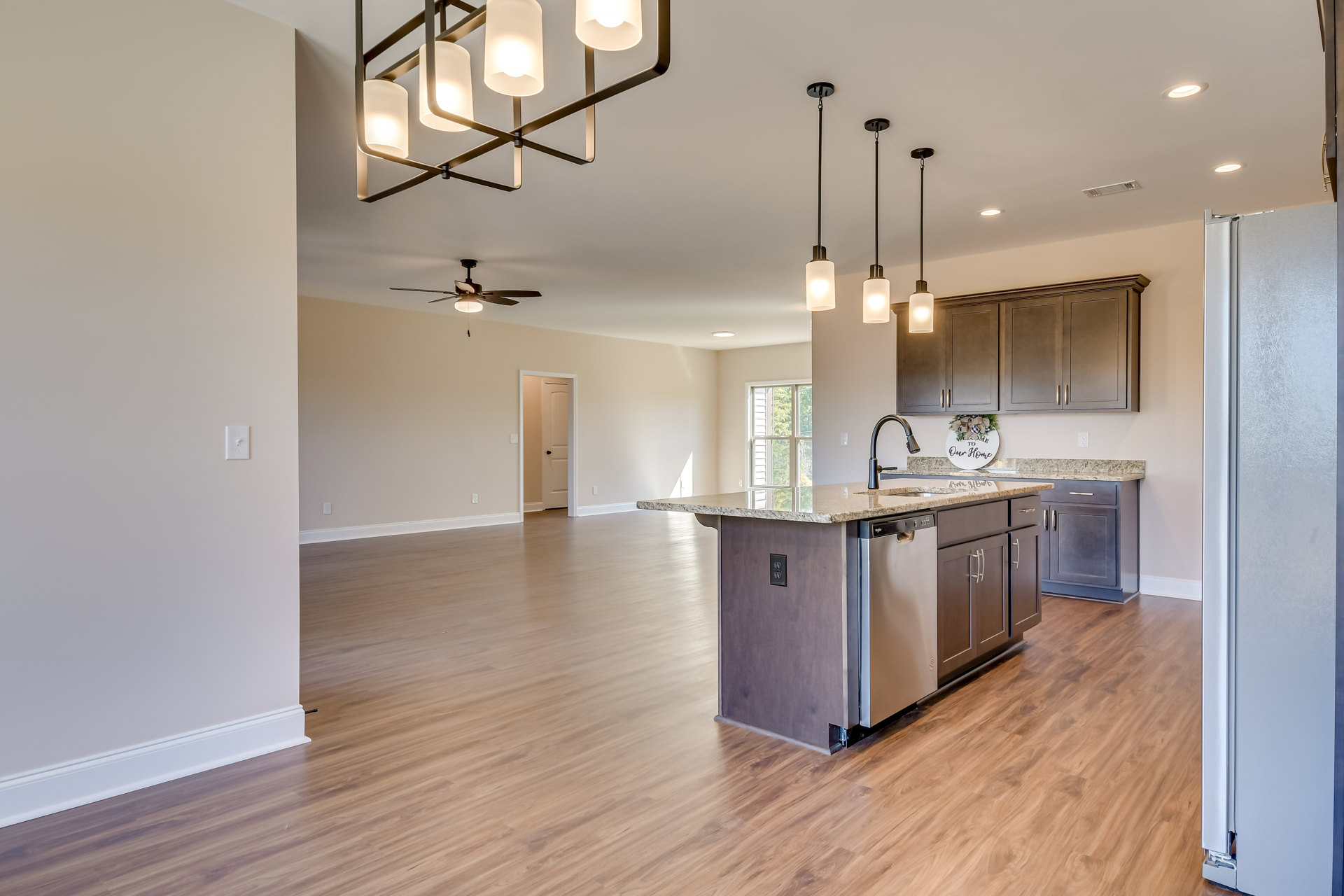 Open kitchen and dining area featuring wood flooring, white cabinetry, stone countertops, stainless steel sink, ceiling fan, and a decorative chandelier; close-up views include a