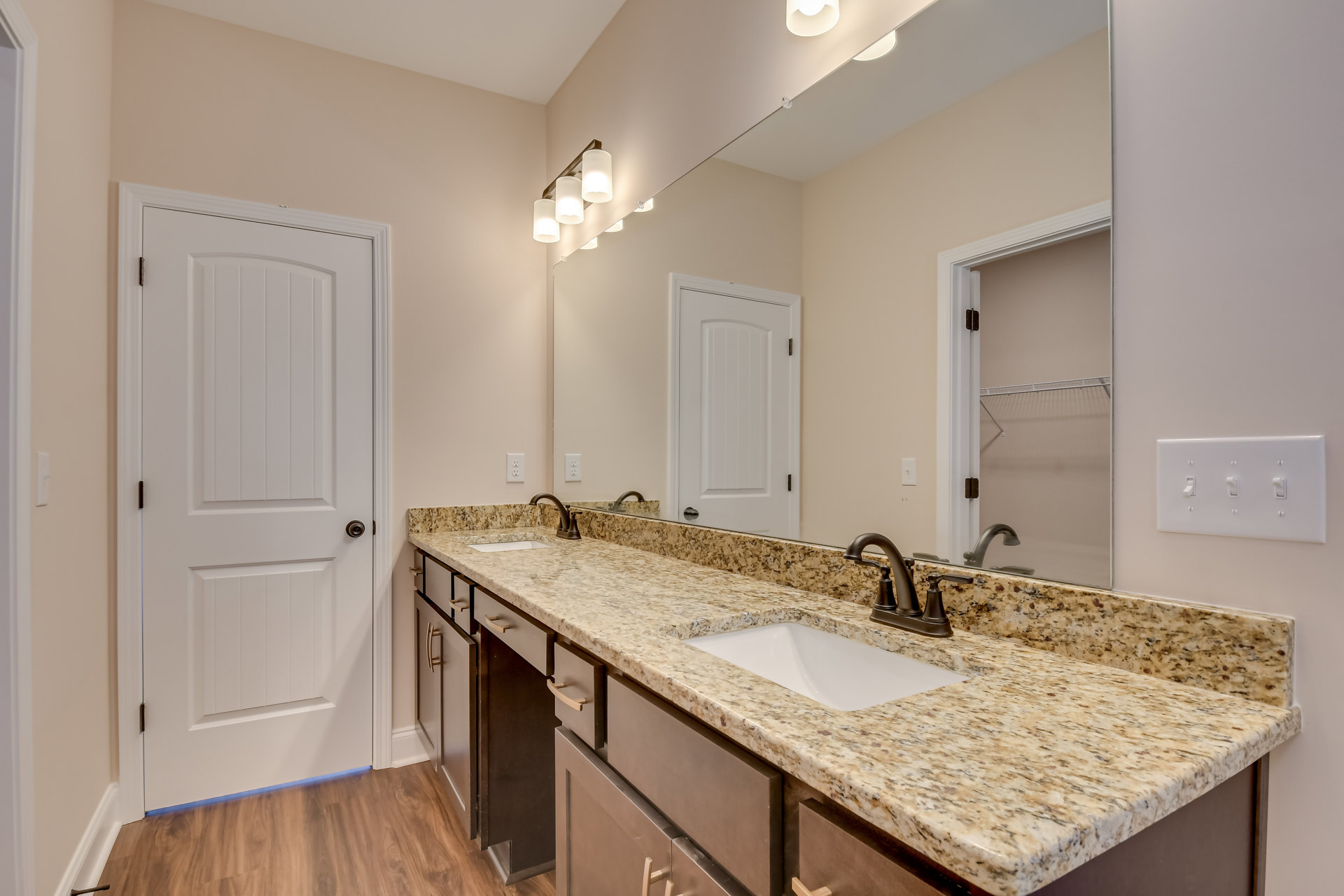 Marble countertop with undermount sink, large frameless mirror above, white cabinetry, black hardware, and tiled walls in a modern bathroom