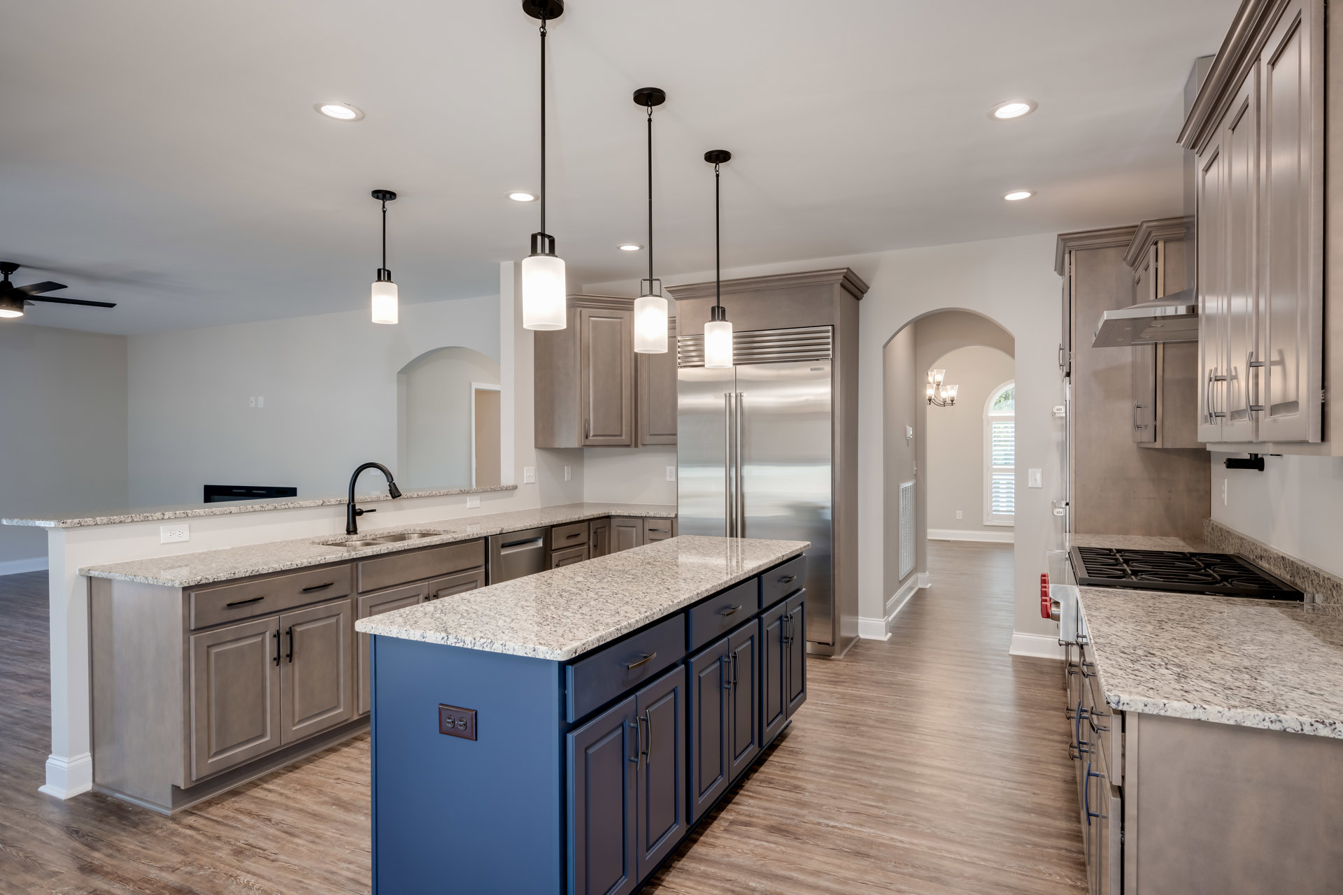 Kitchen featuring granite countertops, spacious central island with marble finish, white cabinetry, stainless steel refrigerator, tile backsplash, pendant light fixture with white