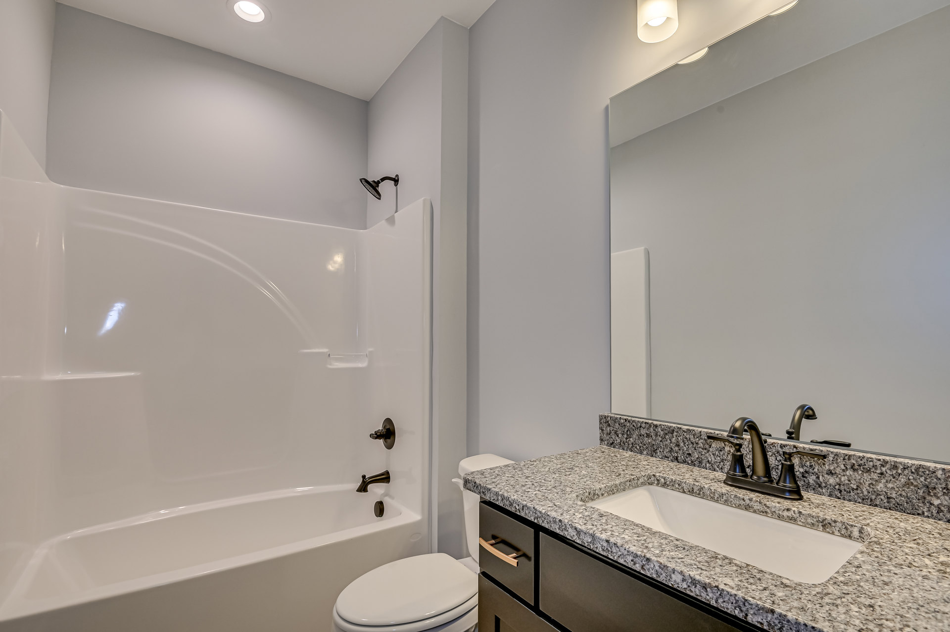Bathroom with white tile walls, marble countertop sink, chrome faucet, white toilet, and glass-enclosed shower.