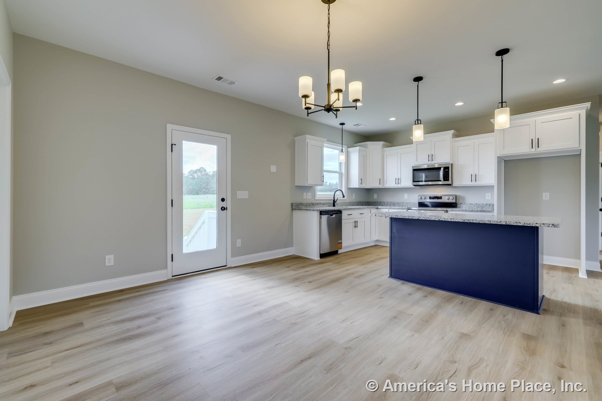 Open concept kitchen with white shaker cabinets, granite countertops, navy blue island base, pendant and chandelier lighting, stainless appliances, light wood flooring, glass door