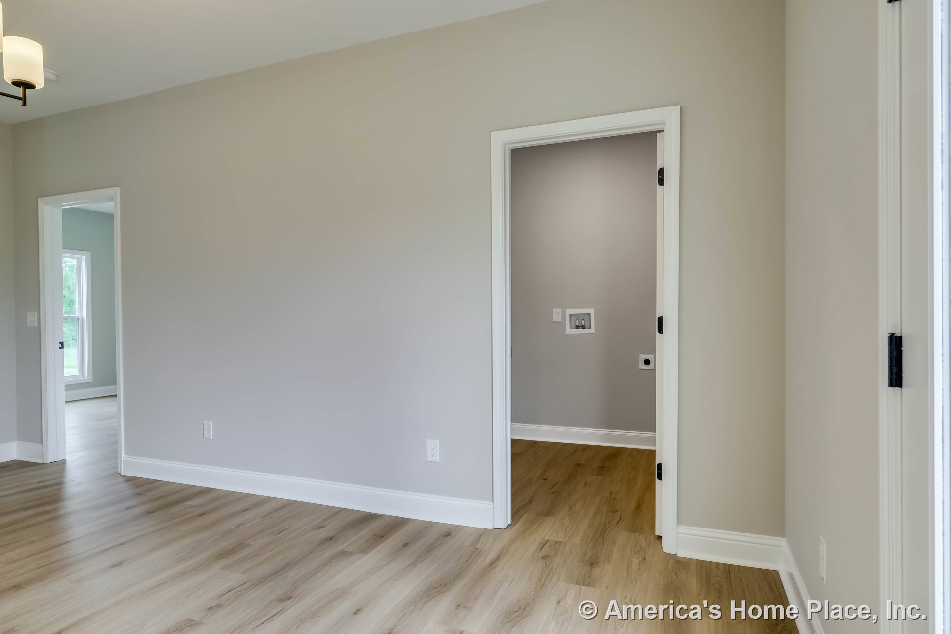 Laundry room with utility hookups, light wood plank flooring, neutral painted walls, white trim and baseboards, interior doorways, ceiling light fixture, modern finishes, open