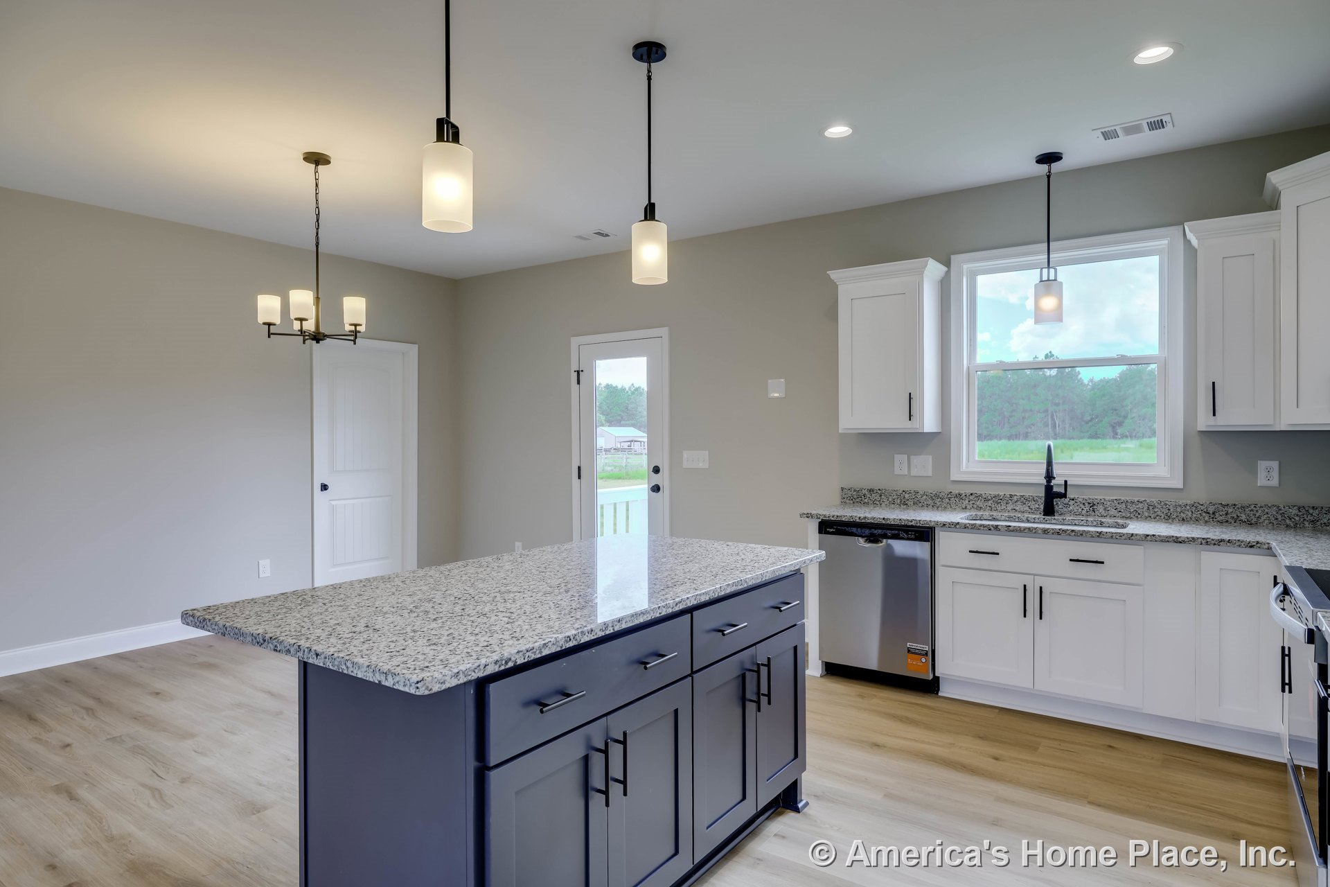 Large central kitchen island with granite countertops, white shaker cabinets, stainless steel dishwasher, pendant and recessed lighting, spacious window above sink, light wood