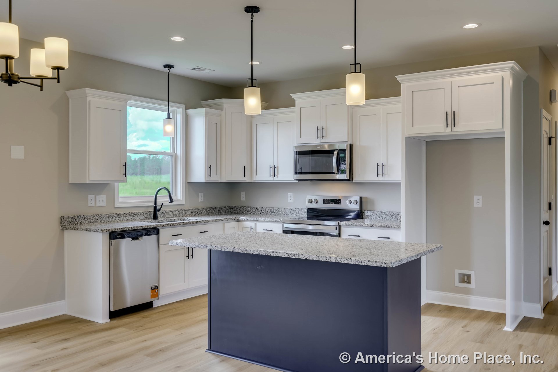 White shaker cabinets with granite island countertop, stainless steel oven and built-in microwave, pendant and recessed ceiling lights, window above sink, light wood flooring