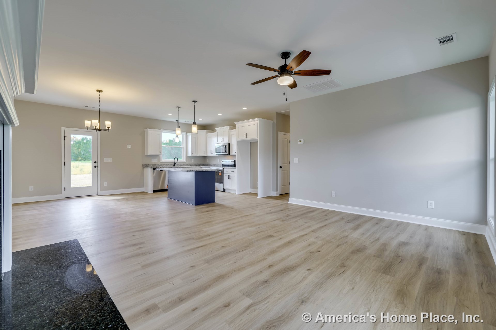 Open concept living area with light wood plank flooring, white kitchen cabinets, granite countertops, pendant and chandelier lighting, ceiling fan with light, trimmed windows and