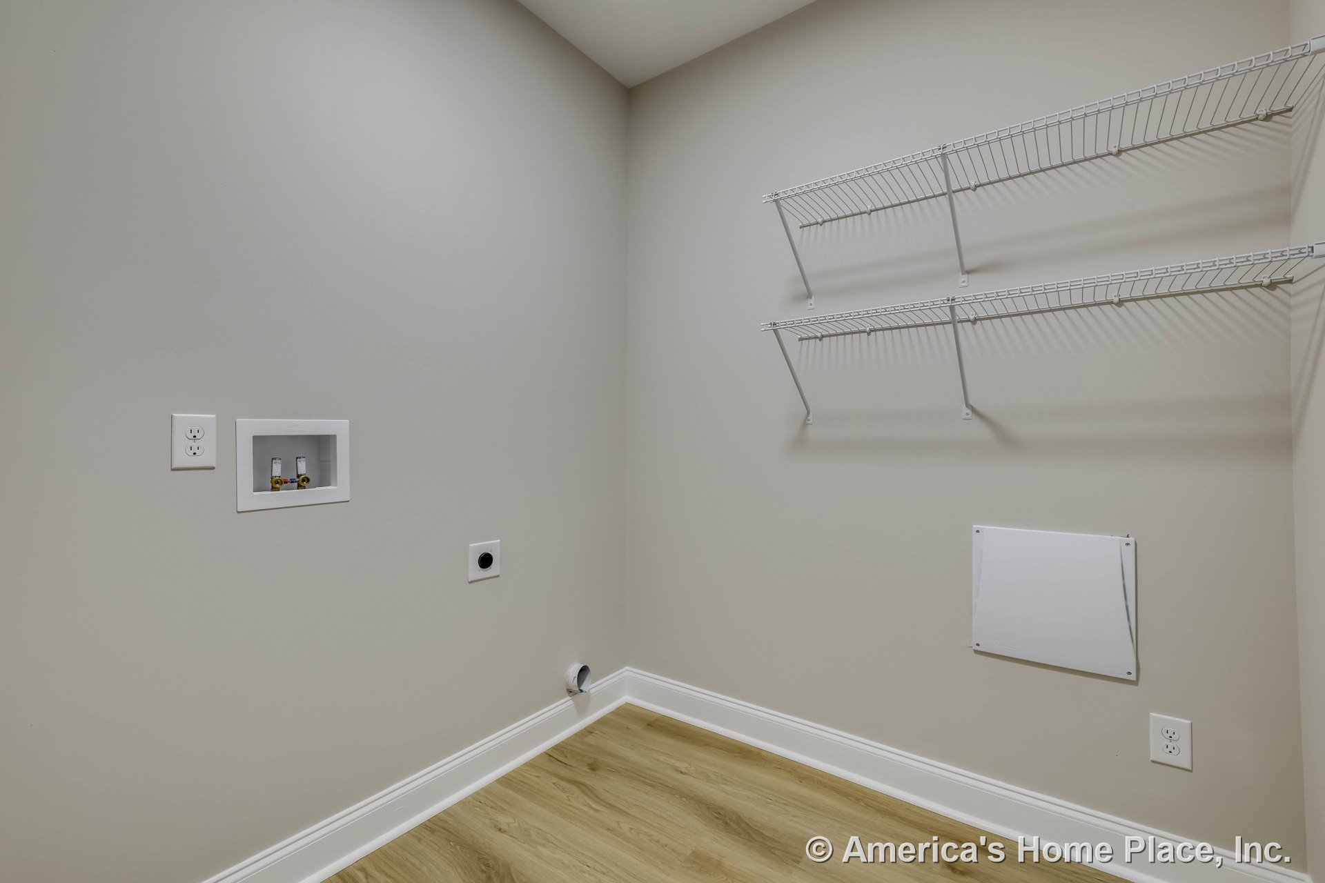 Laundry room with washer and dryer hookups, two wall-mounted wire shelves, light wood flooring, white baseboards, utility access panel, wall outlets, and neutral painted walls.